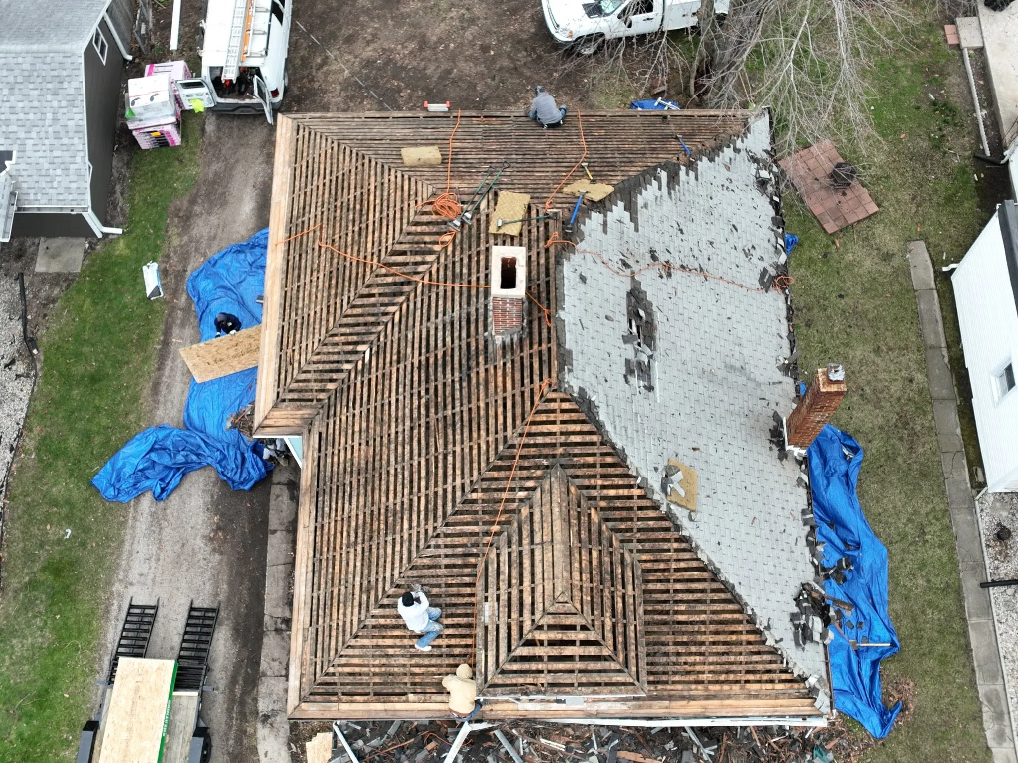 Overhead view of the house with the old shingles half stripped, showing the original spaced board decking underneath