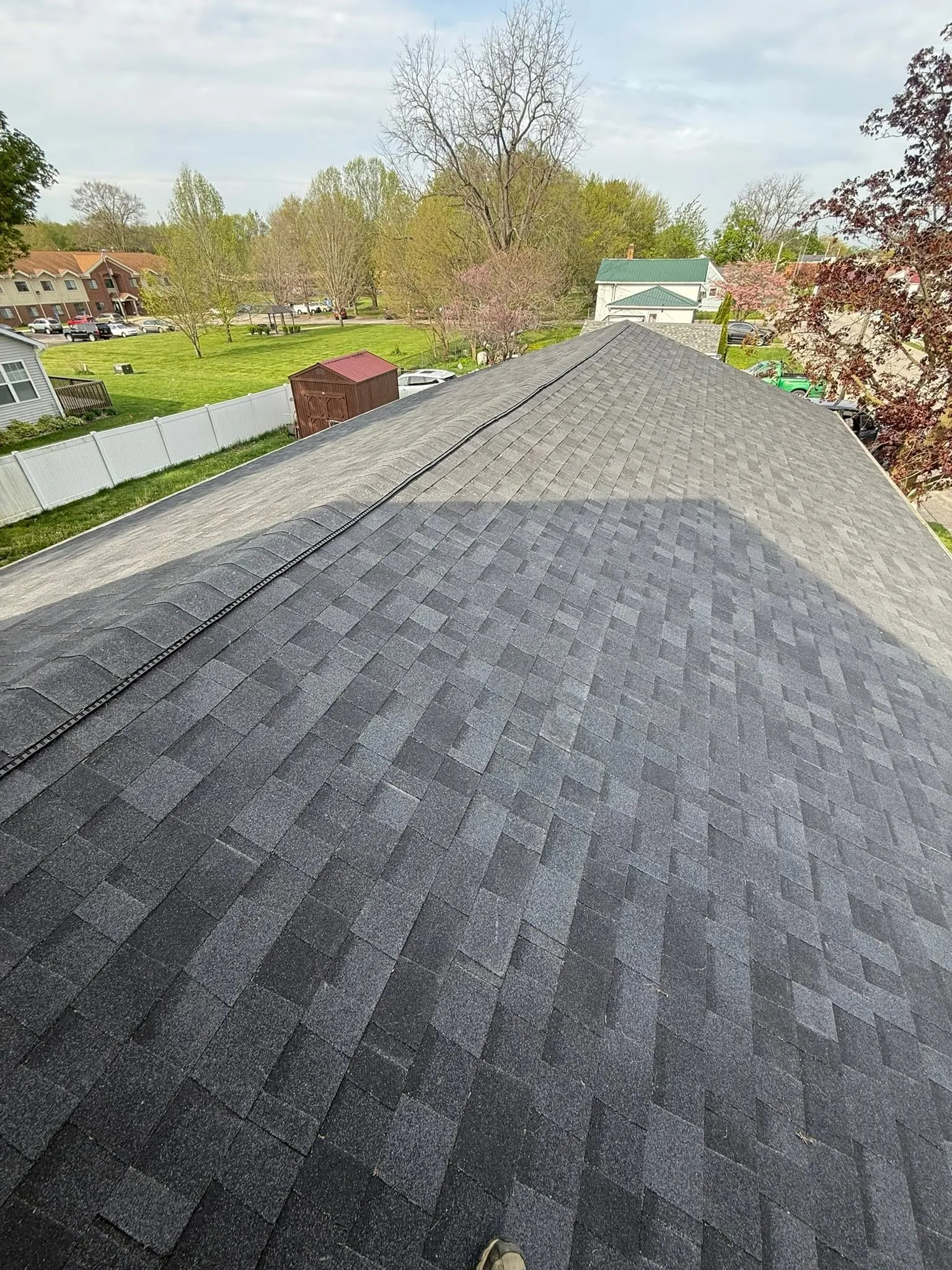Looking down the new shingle roof from the peak, with ridge vent running along the ridge line