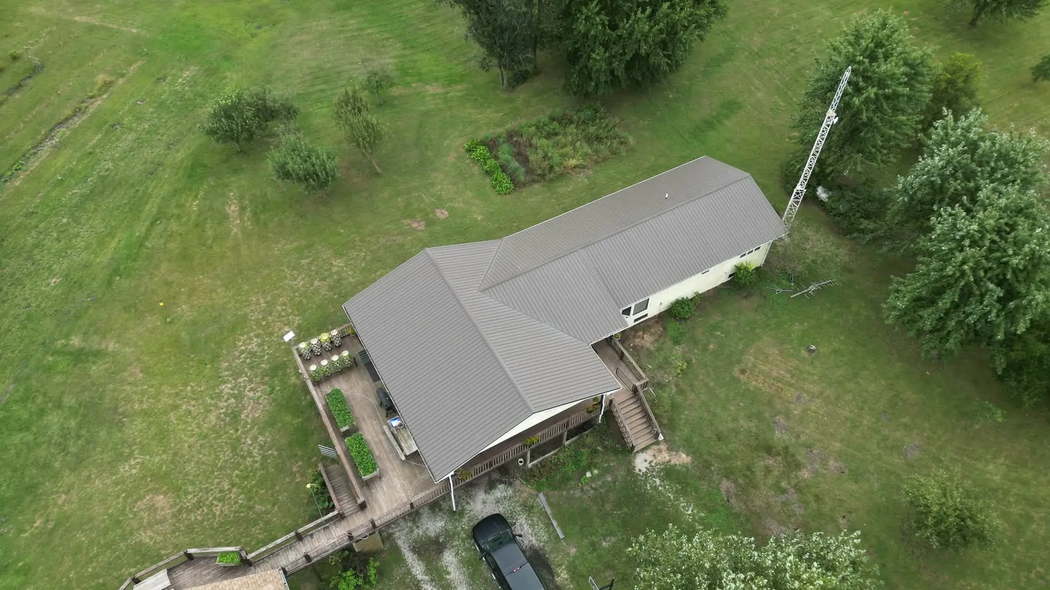 The finished Burnished Slate metal roof from above, on a ranch home with a deck and raised garden beds