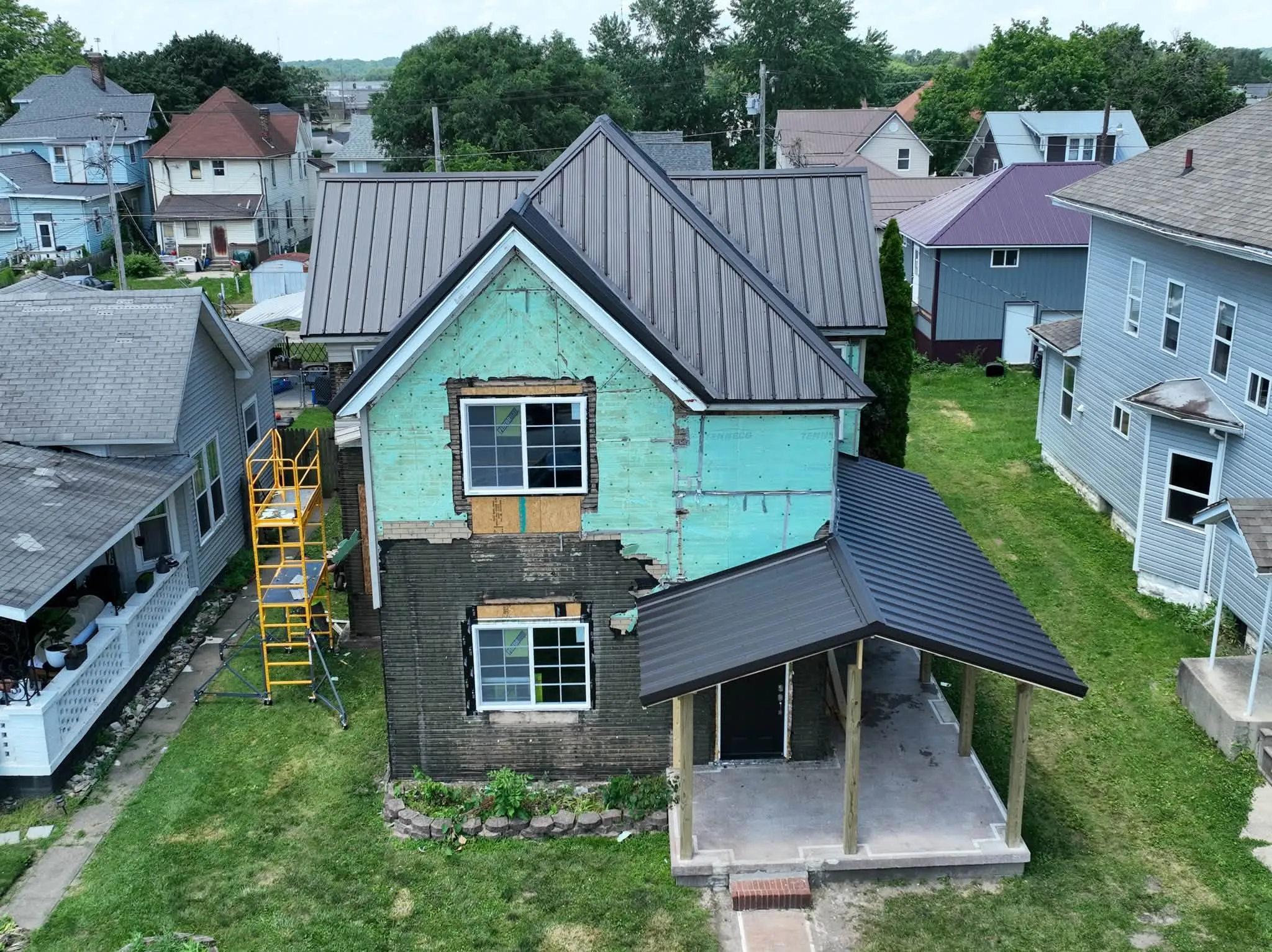 The new Dark Bronze metal roof on a two-story house in Peru, with the newly framed front porch below it