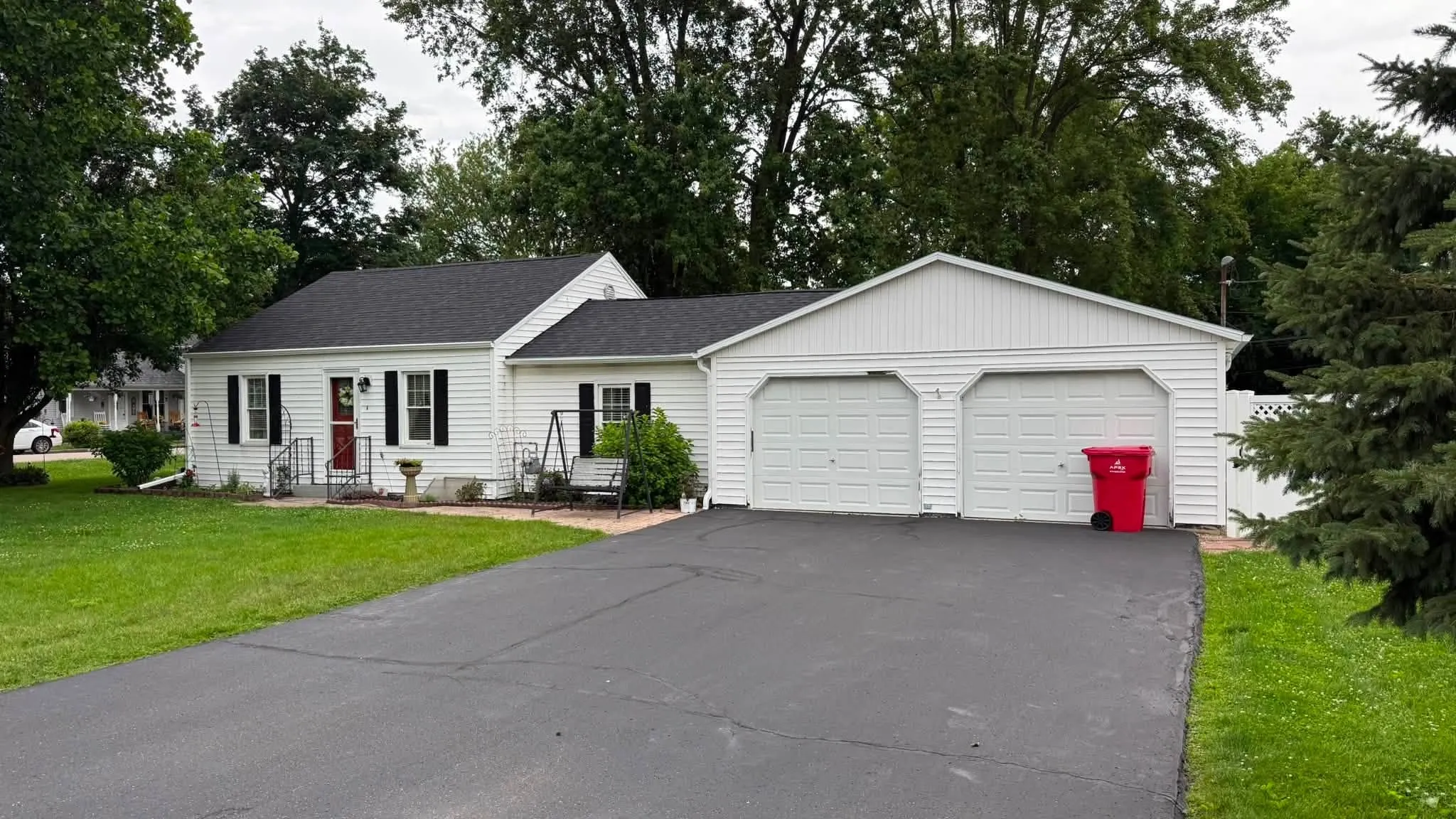The finished white house with its new black shingle roof, black shutters and attached double garage