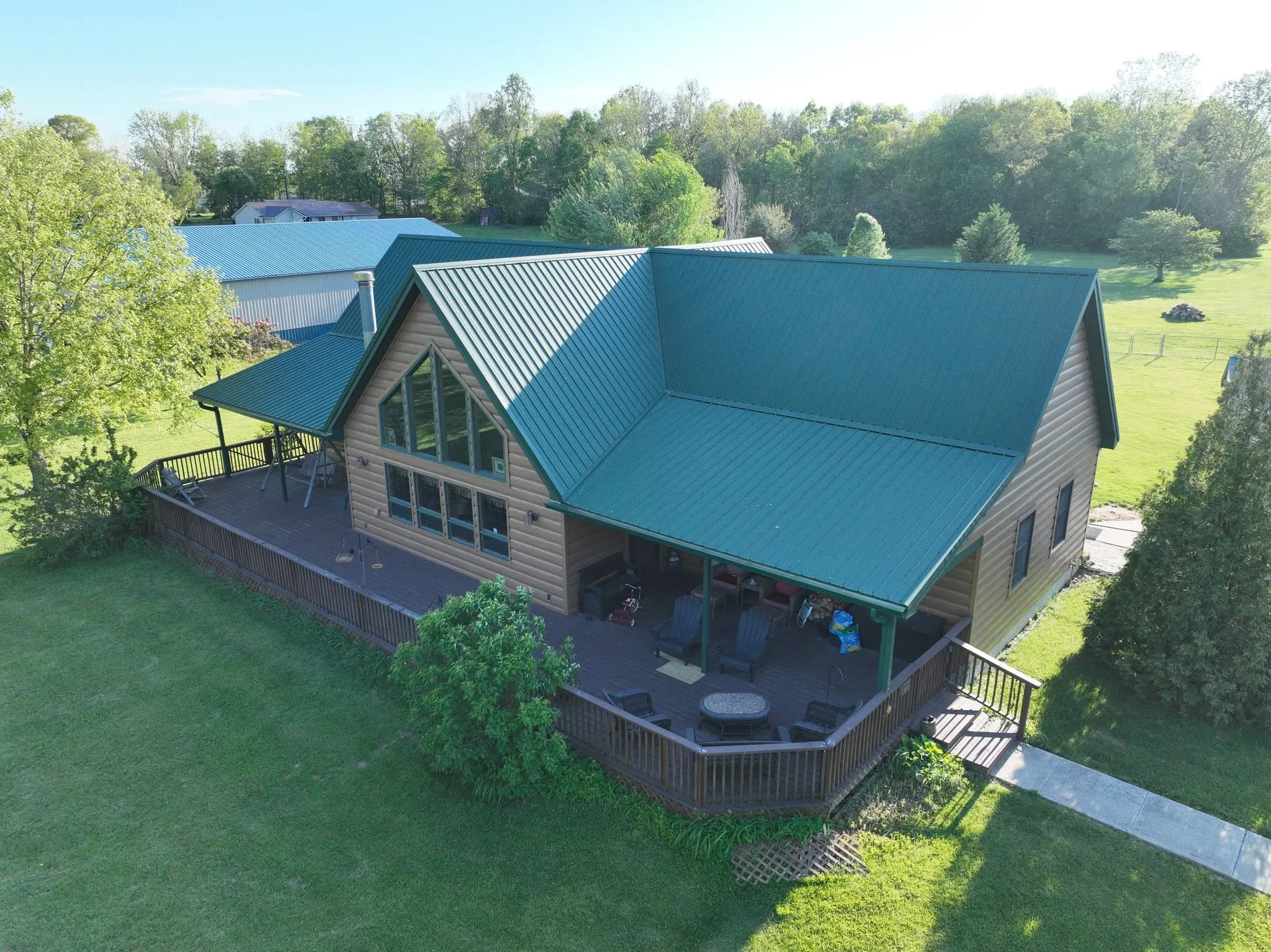 The finished Hunter Green metal roof on a home outside Logansport, seen from the air above the covered deck