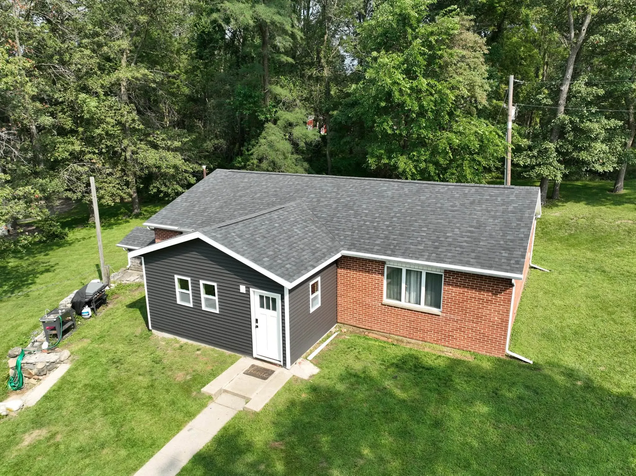The brick home from above, with the new dark gray addition at one end and the new Onyx Black roof running over both