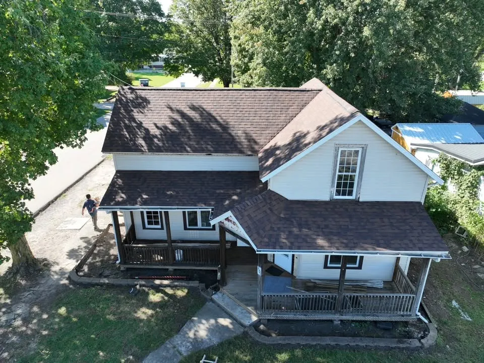 The finished house from above the front yard, with its new Burnt Sienna roof over the main house and both porches