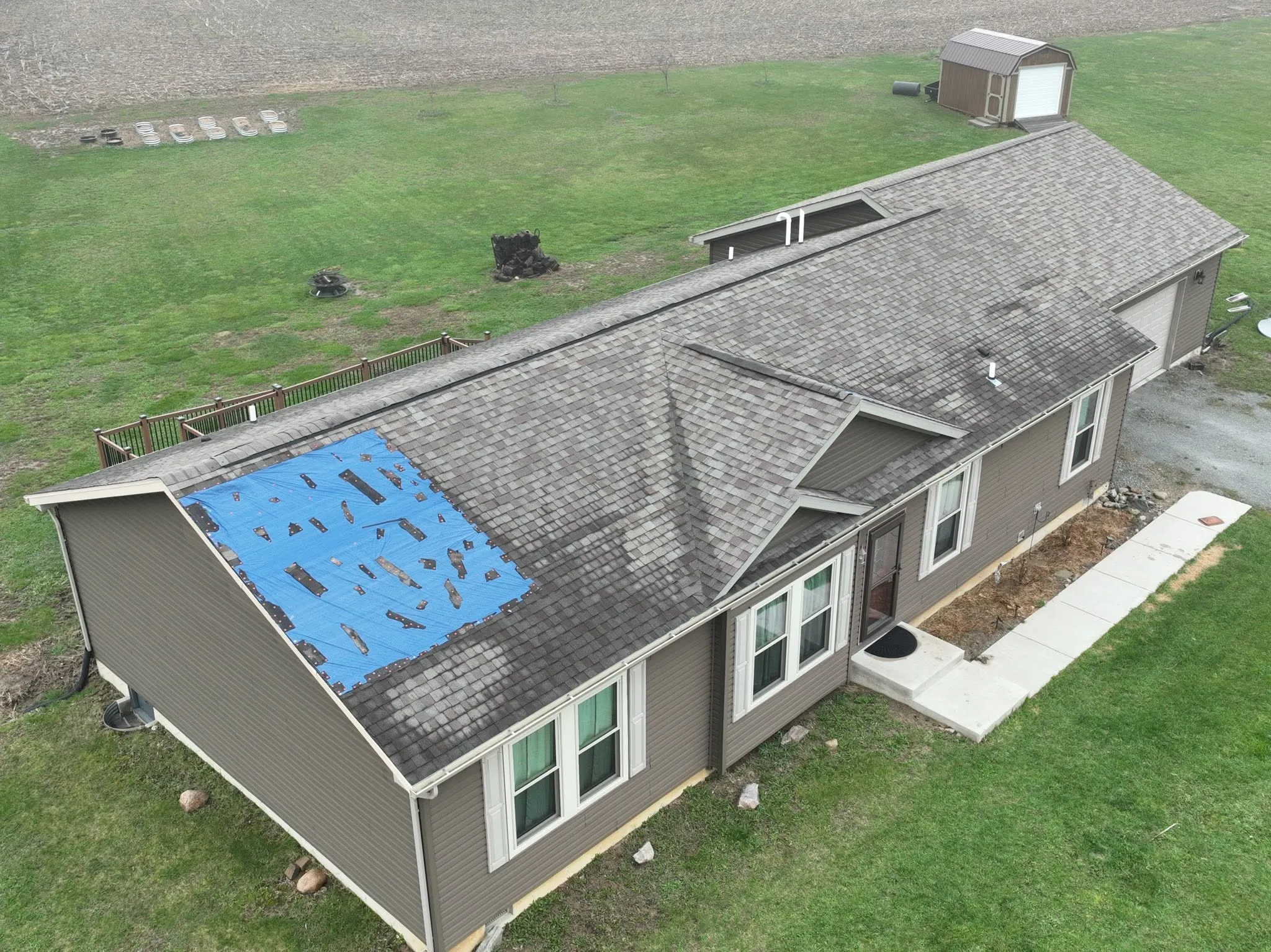 The old shingle roof before the work, with a blue tarp covering a section of one slope