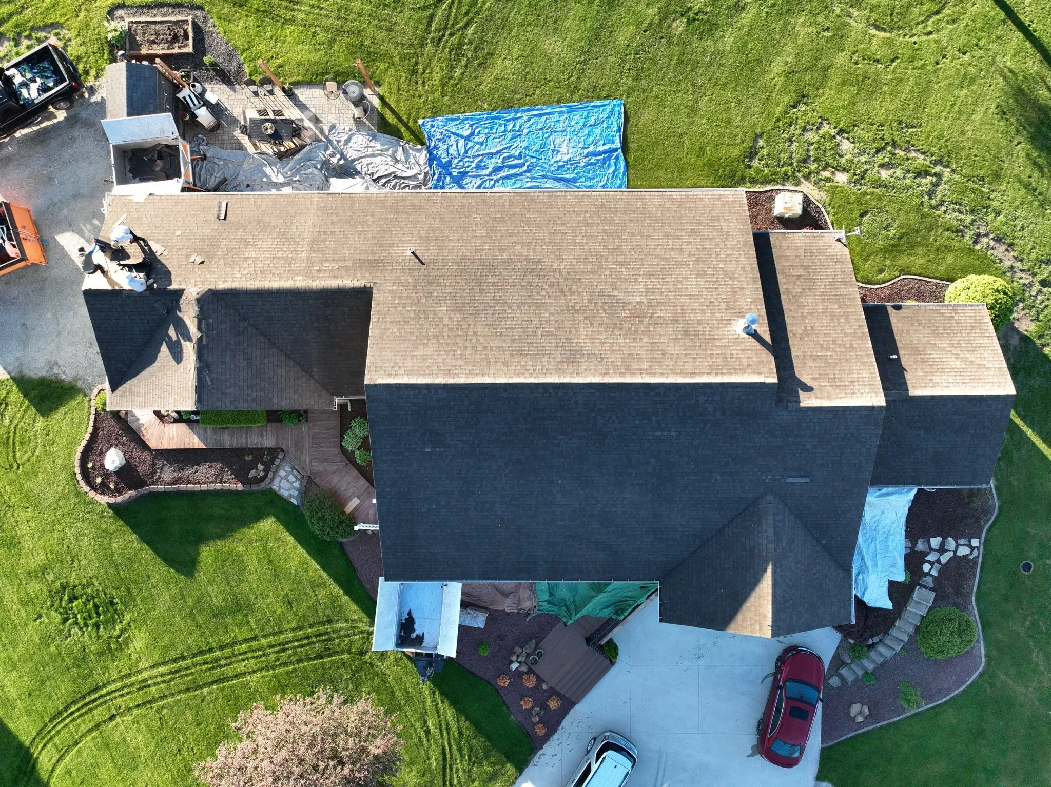 Overhead view mid-install, with new shingles covering about half the roof and underlayment showing on the rest