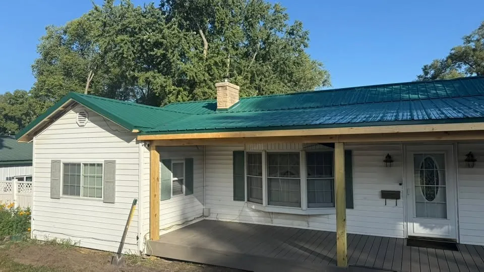 The new roof and covered deck from the other end of the house, with the chimney and the bay window behind the posts