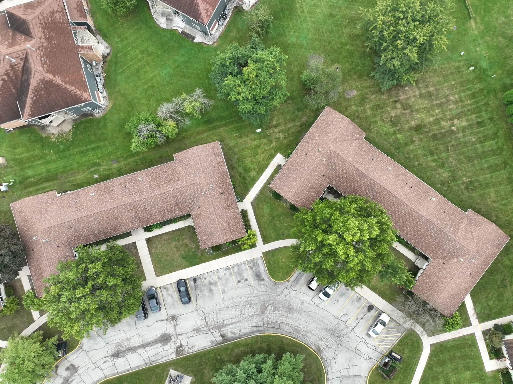 Overhead view of two of the L-shaped buildings with their new roofs, either side of the curving parking lot