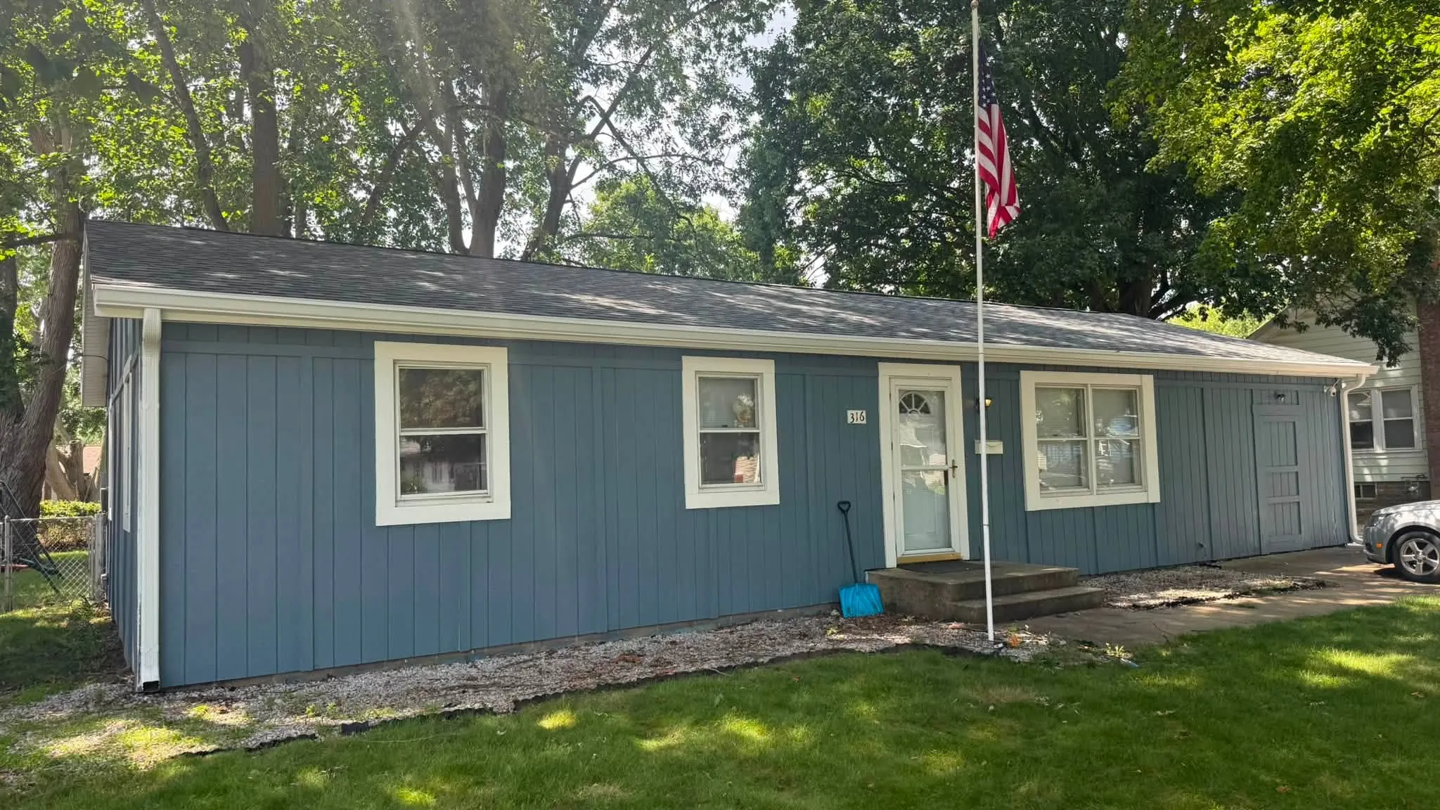 The finished house from the front, with the new Estate Gray roof above blue board-and-batten siding and new white gutters