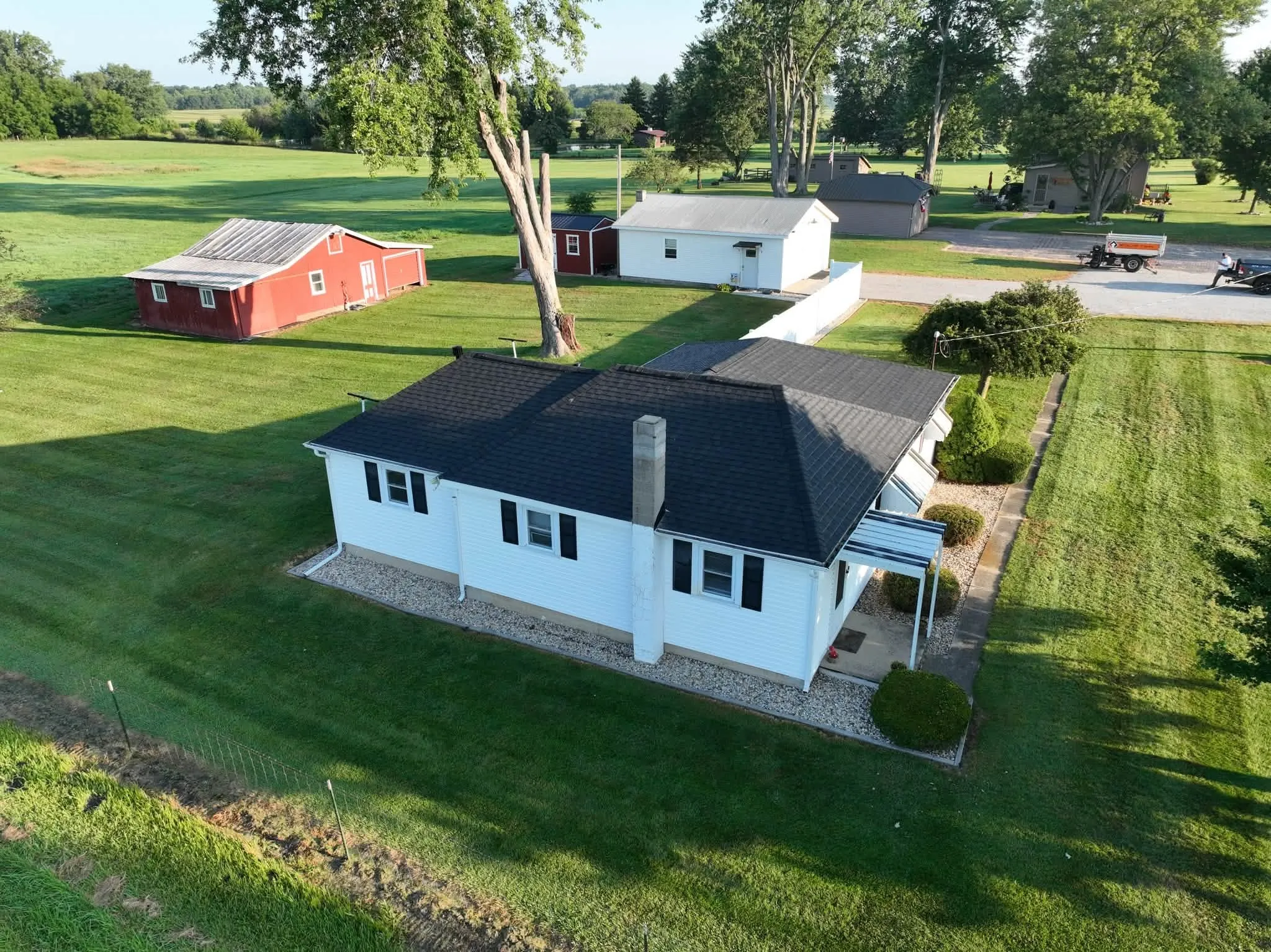 The house from the other side, with the chimney, the yard, and the outbuildings across the road