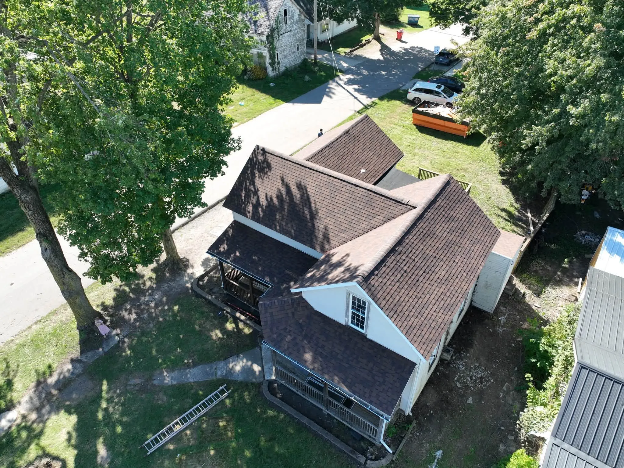 The house from the side, showing the new roof across the main gable, the wing, and the screened porch