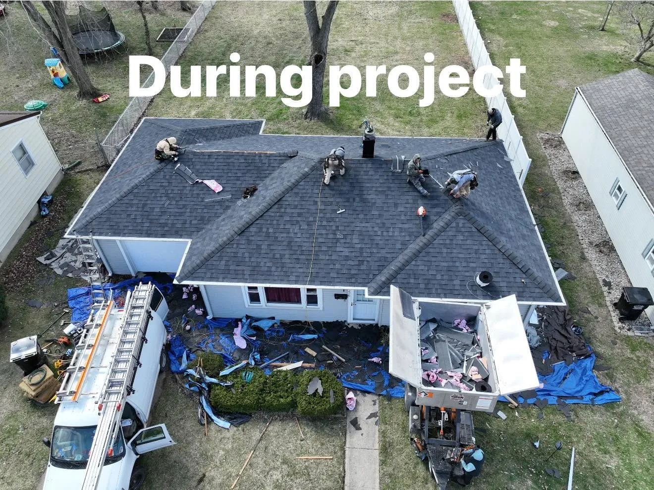 The crew part way through the install, with tarps and the dump trailer set up below, labelled During project