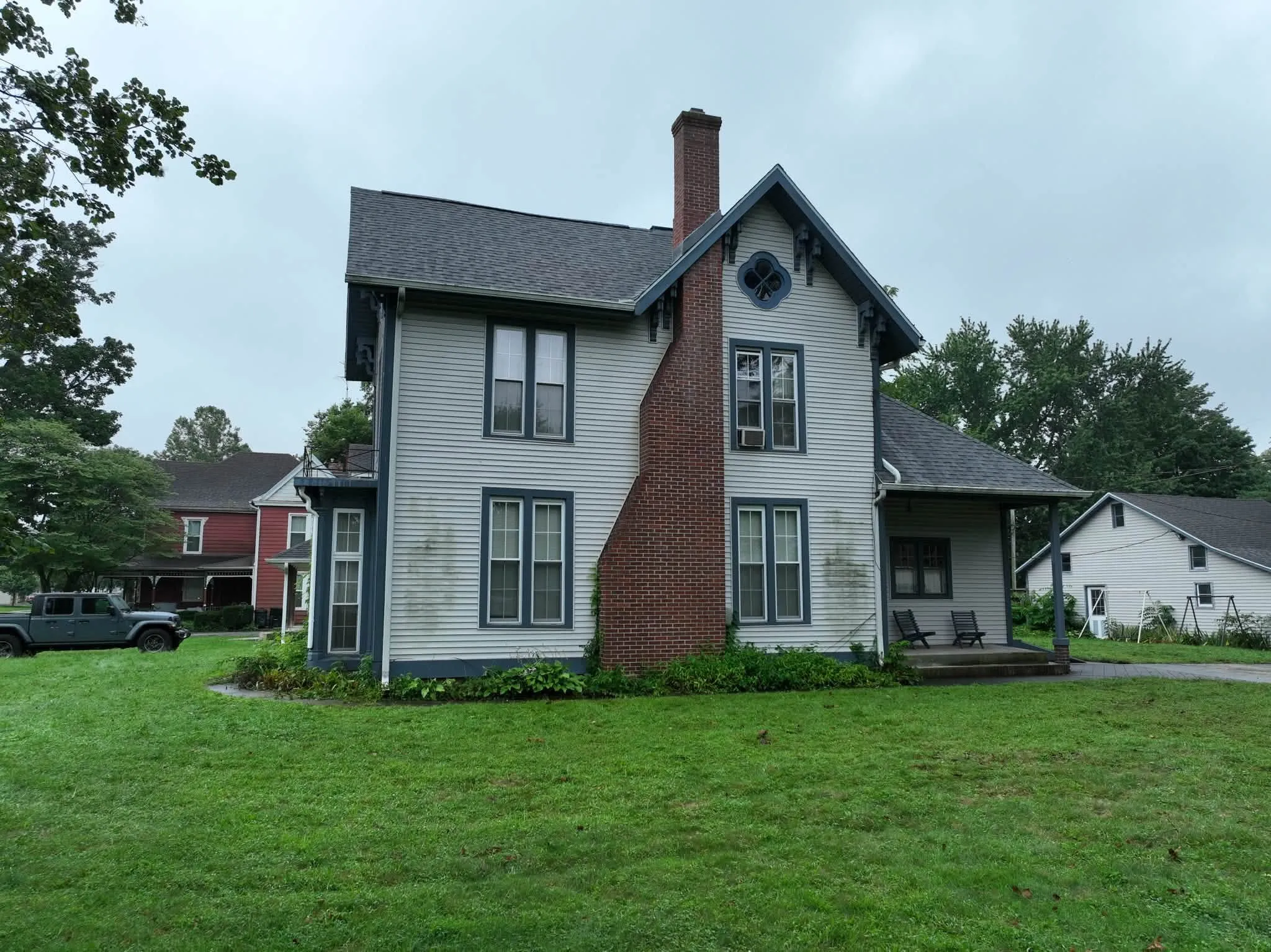 The side of the house from the yard, with the chimney, the steep gables, and the porch roof
