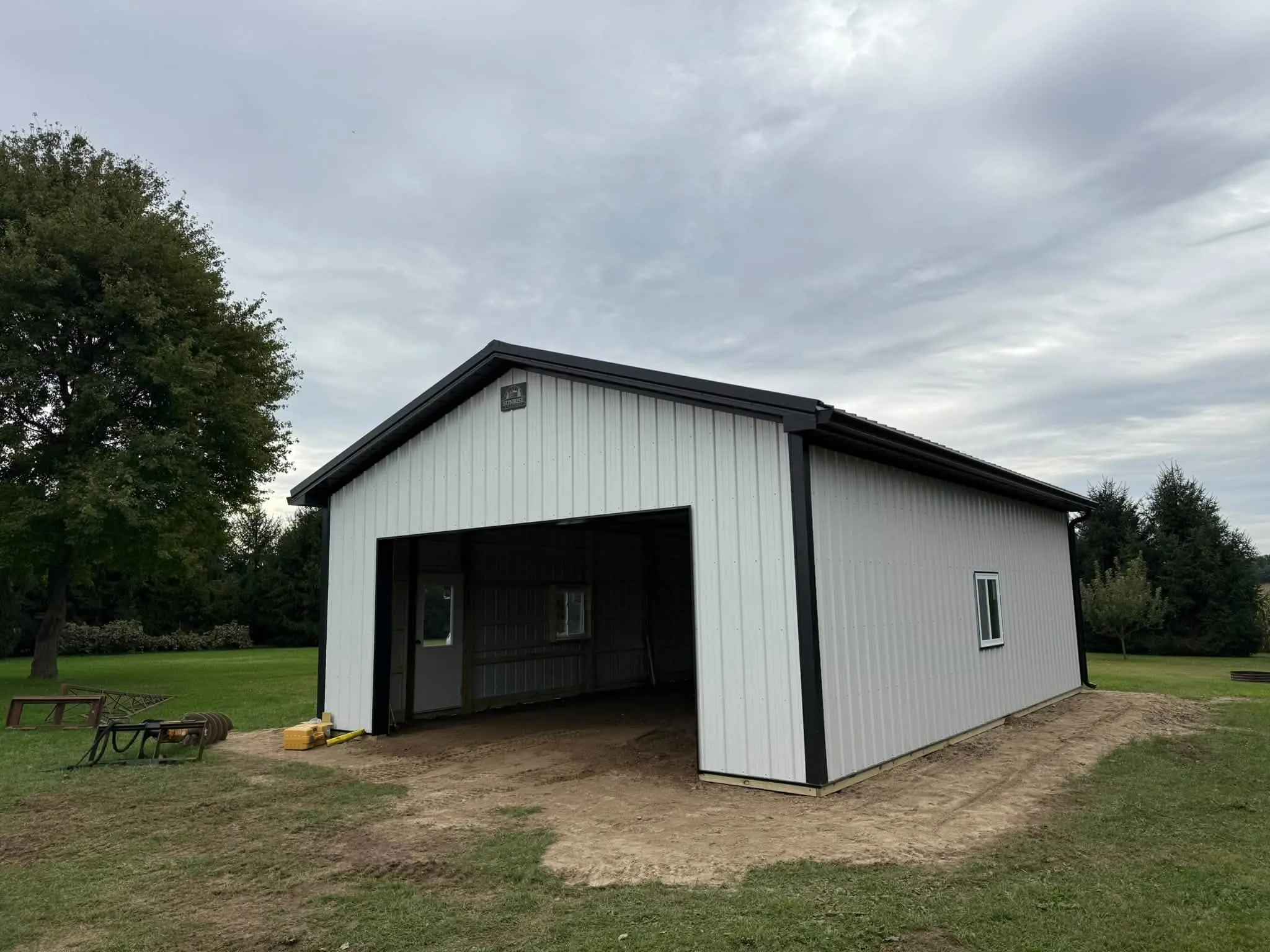 The barn from the front corner, looking into the open bay, with evergreens behind it
