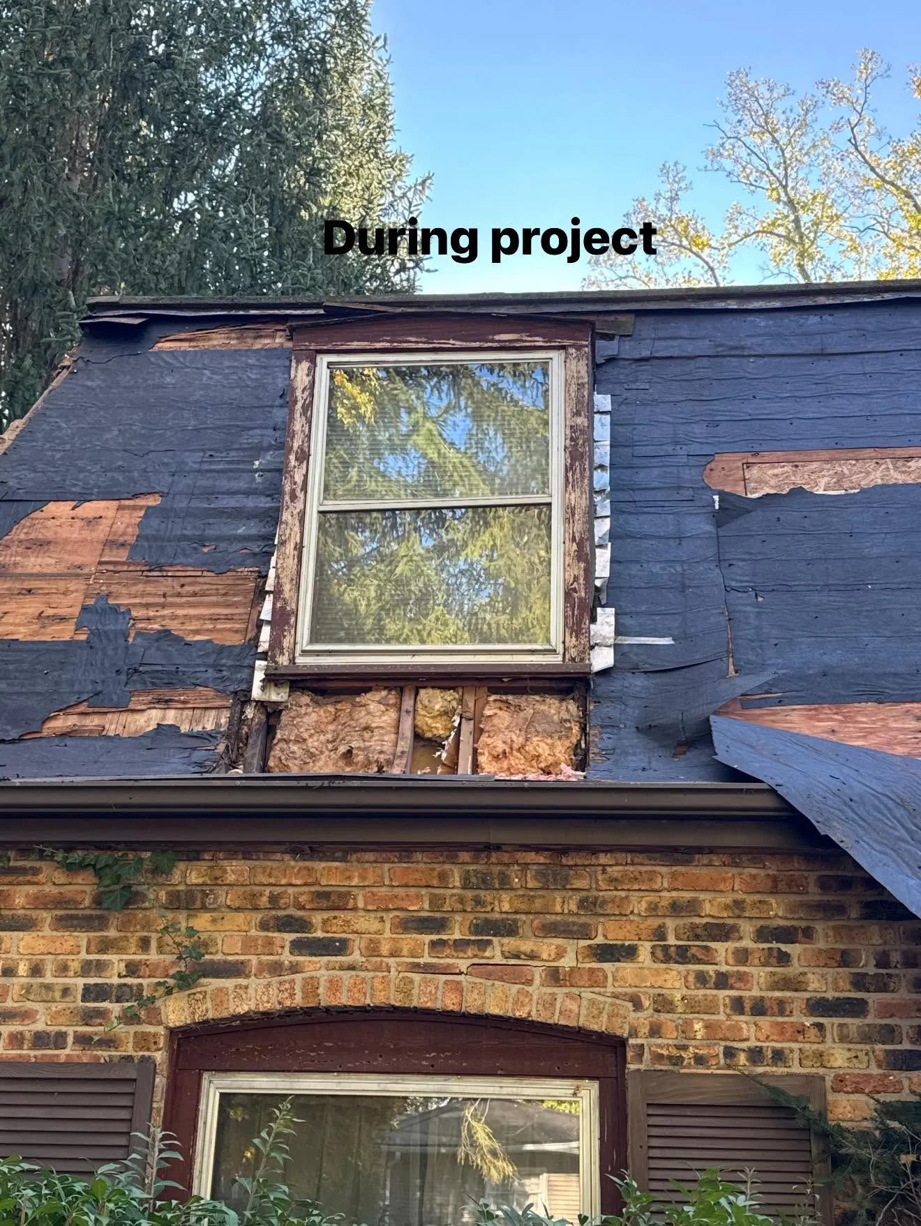 Tear-off in progress at one of the dormers, with the old covering stripped back around the window, labelled During project