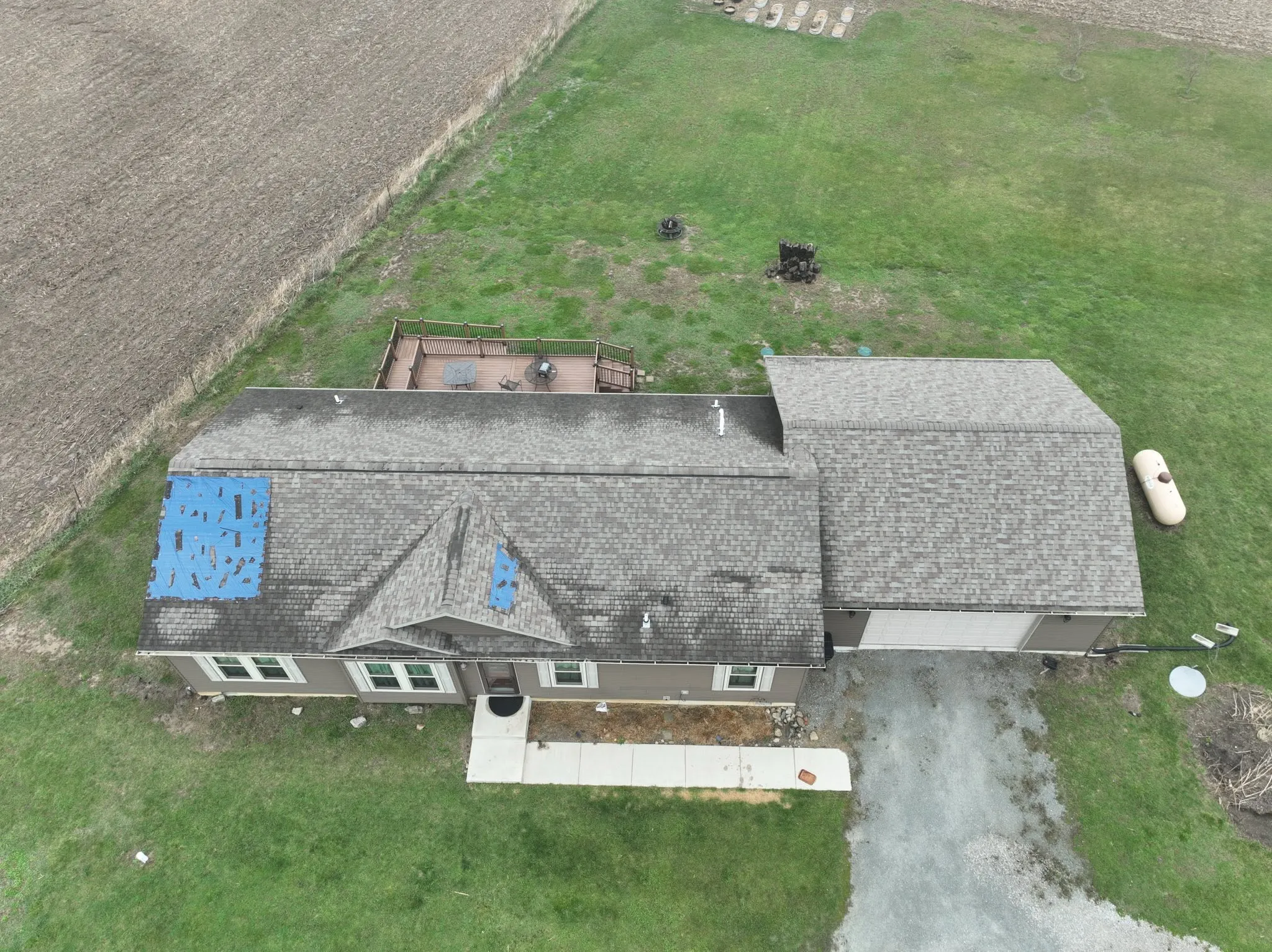 Overhead view of the old roof, showing worn shingles and two tarped areas