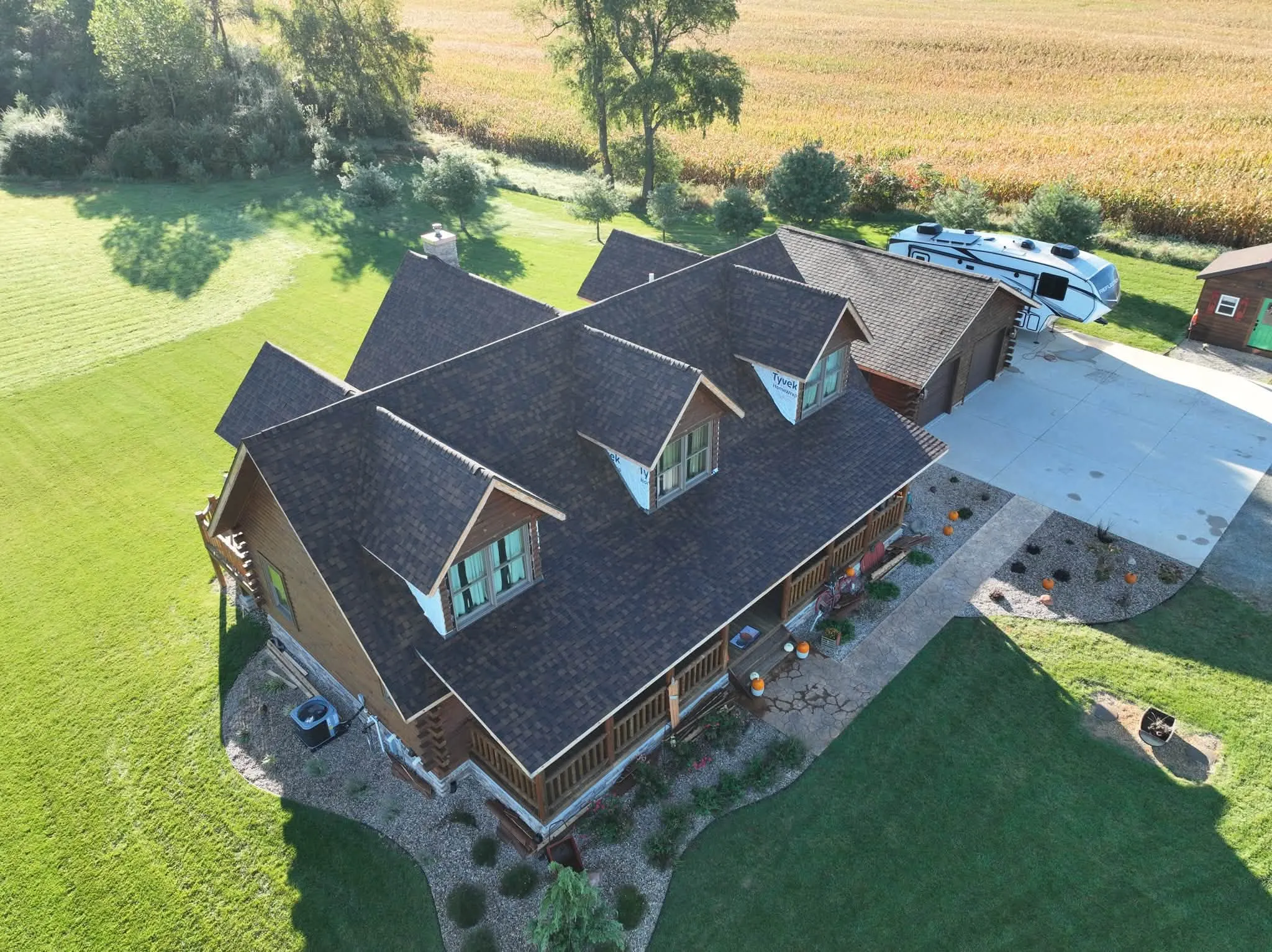 The house from the other front corner, showing the dormers, the porch roof, and the fields beyond