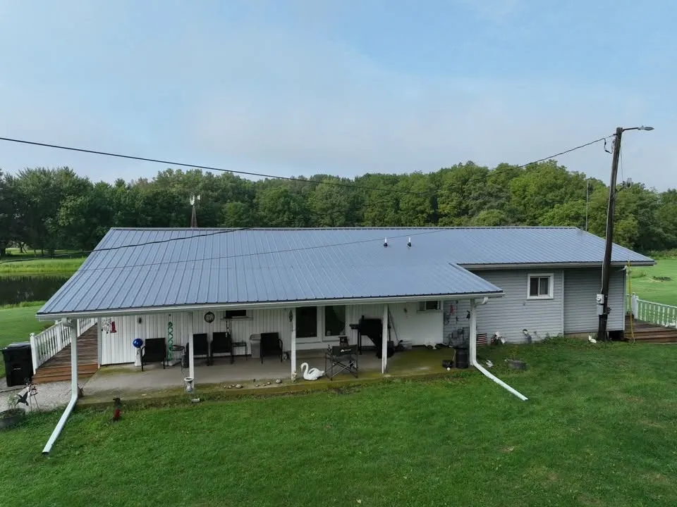 The house from the yard, with the new roof running out over the long covered porch