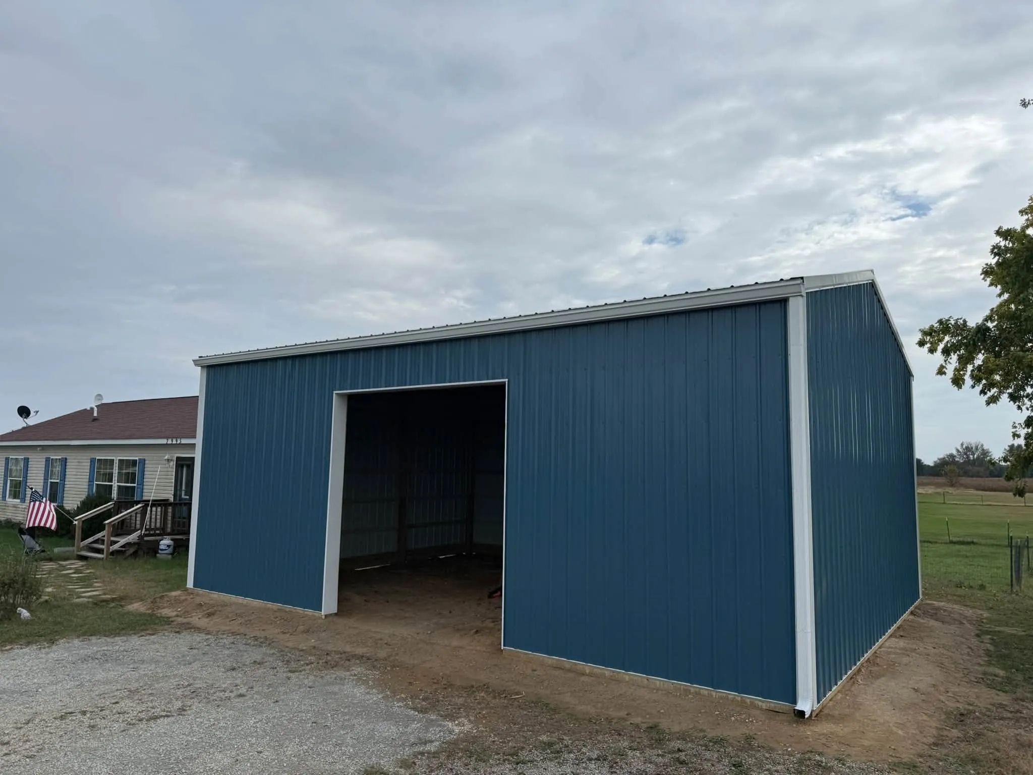 The garage from the other front corner, with the open bay and the neighboring house behind it