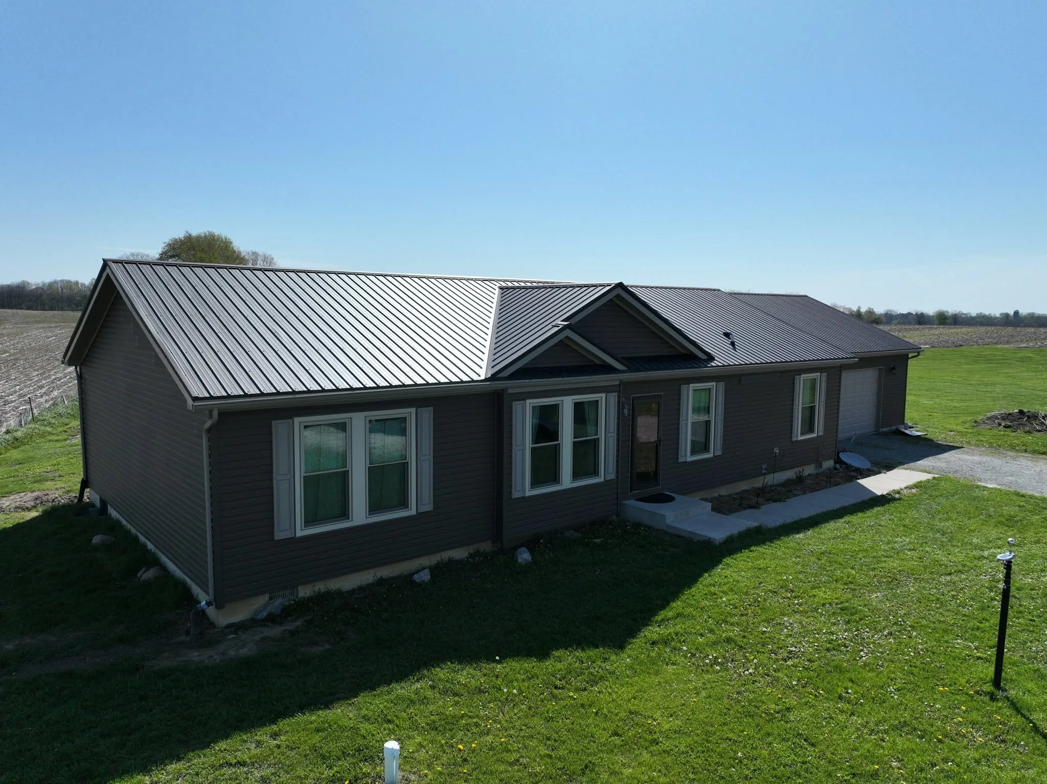 The finished house with its new dark metal roof, seen from the front on a clear day