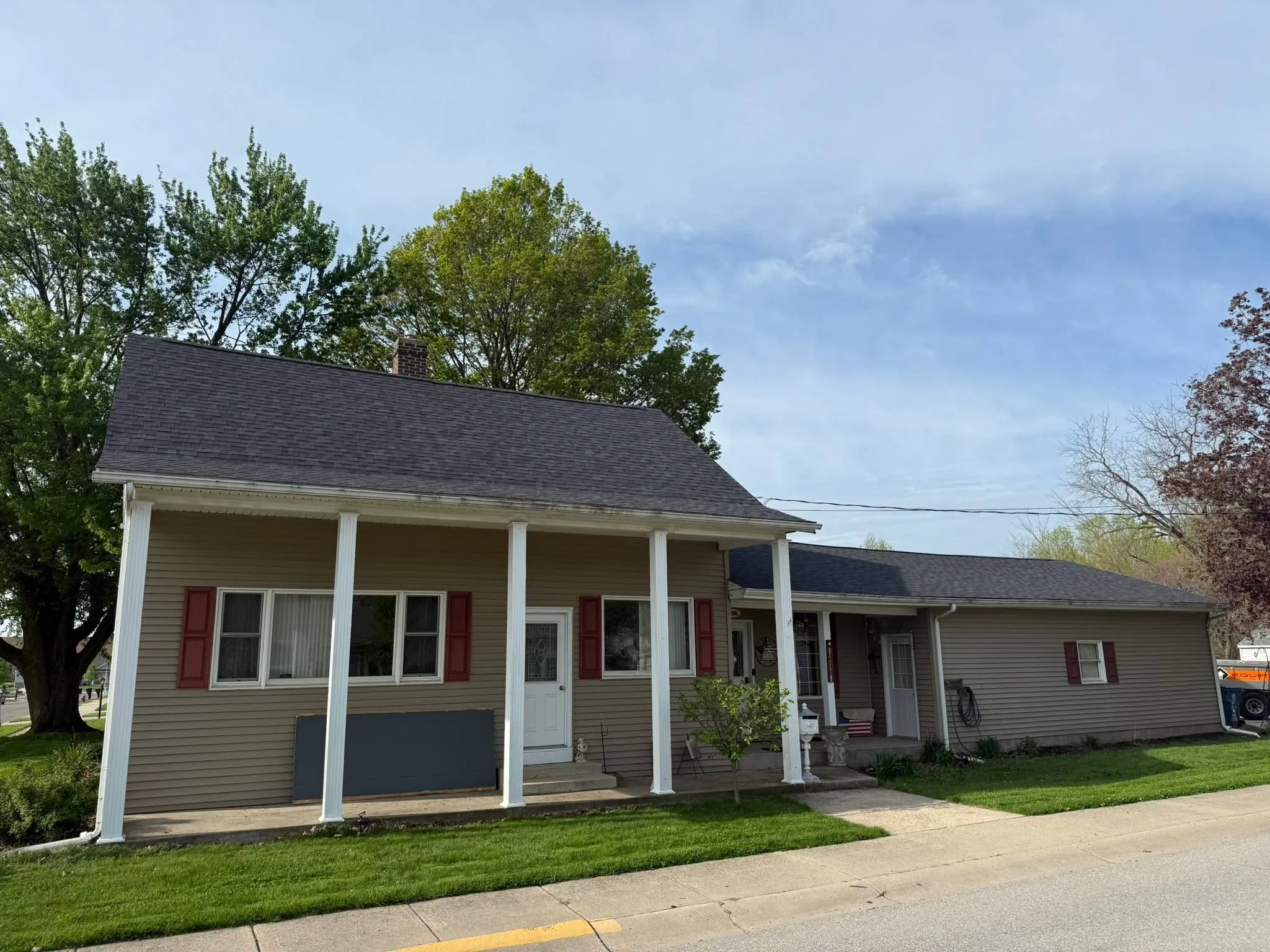 The finished Bremen home from the street, with its new dark shingle roof carrying out over a full-width front porch