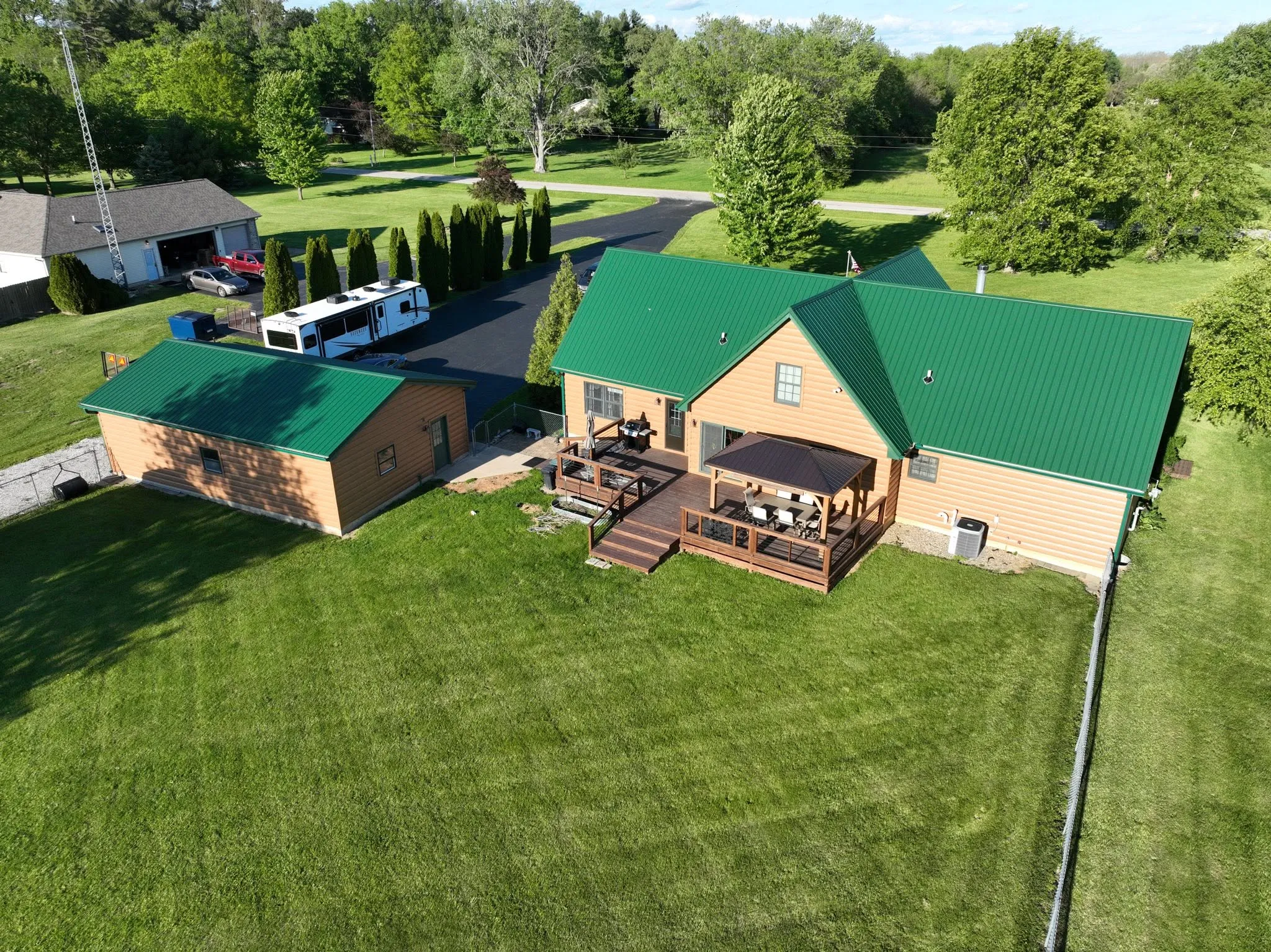 The house and the detached garage from the air, both finished in Hunter Green metal with the deck between them