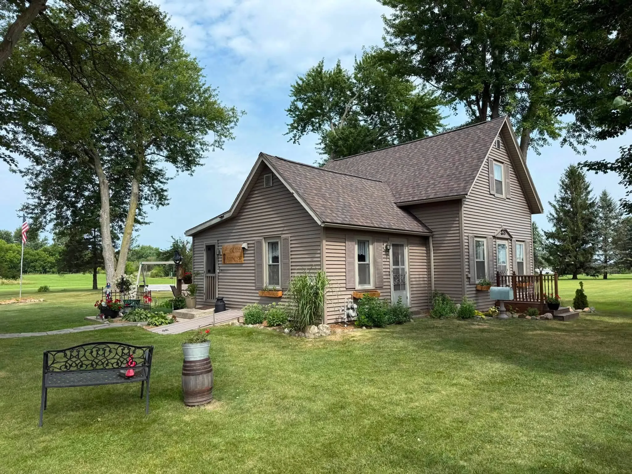 The finished Claypool farmhouse from the front lawn, with its new brown shingle roof over the steep main gable and the front wing