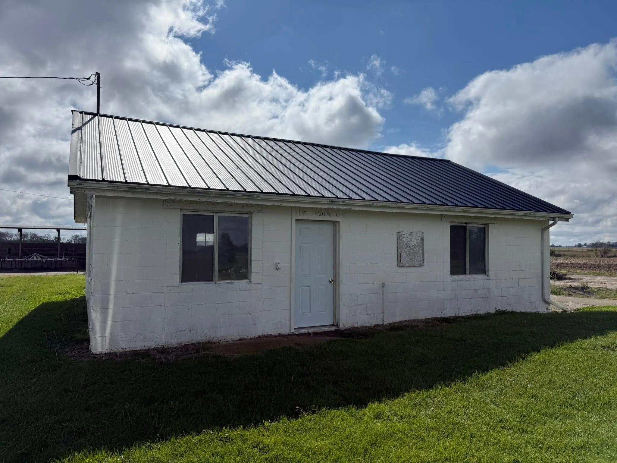 The finished black 28 gauge metal roof on the block barn against a blue sky