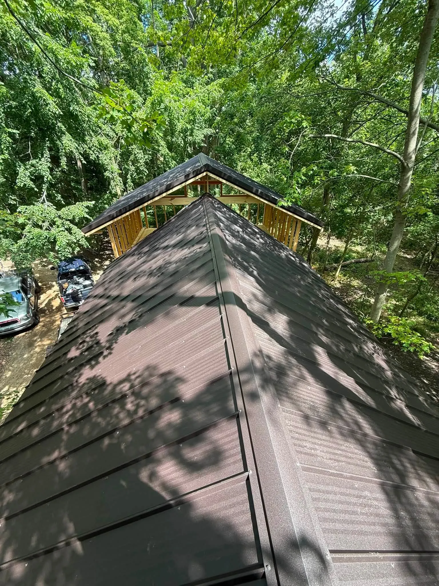 Looking along the ridge of the lower roof toward the framed upper section and its own metal roof