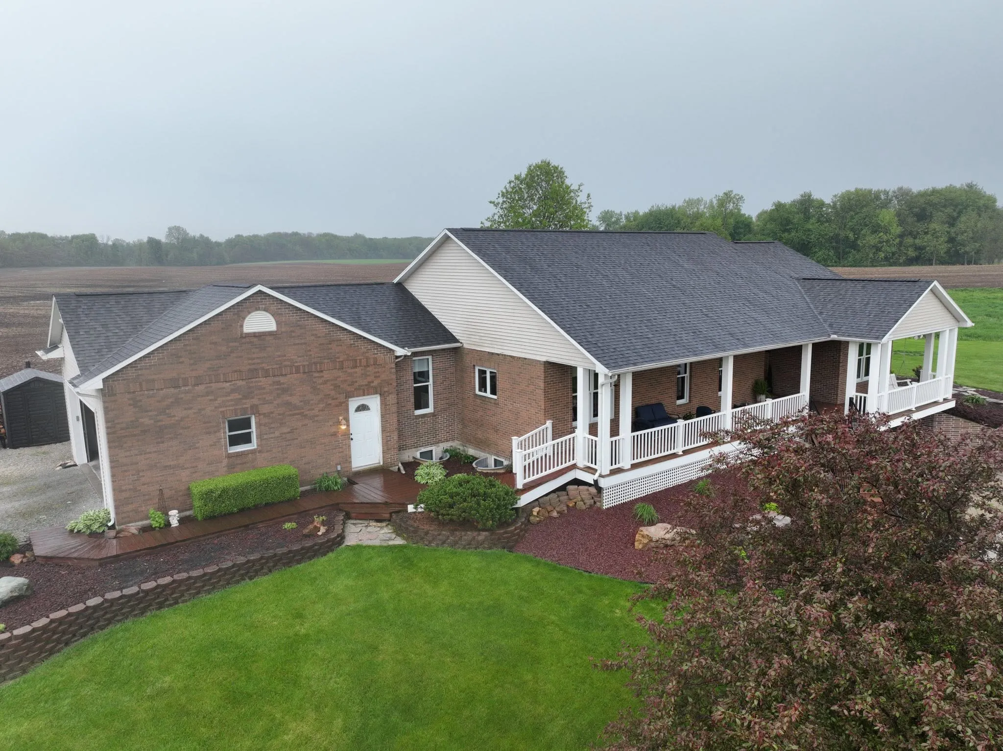 The finished brick ranch in Claypool with its new charcoal shingle roof, seen from the air on an overcast day
