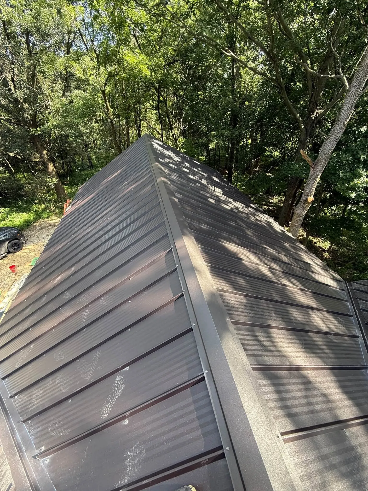 Close view up the hip of the metal roof, with shade from the trees across the panels