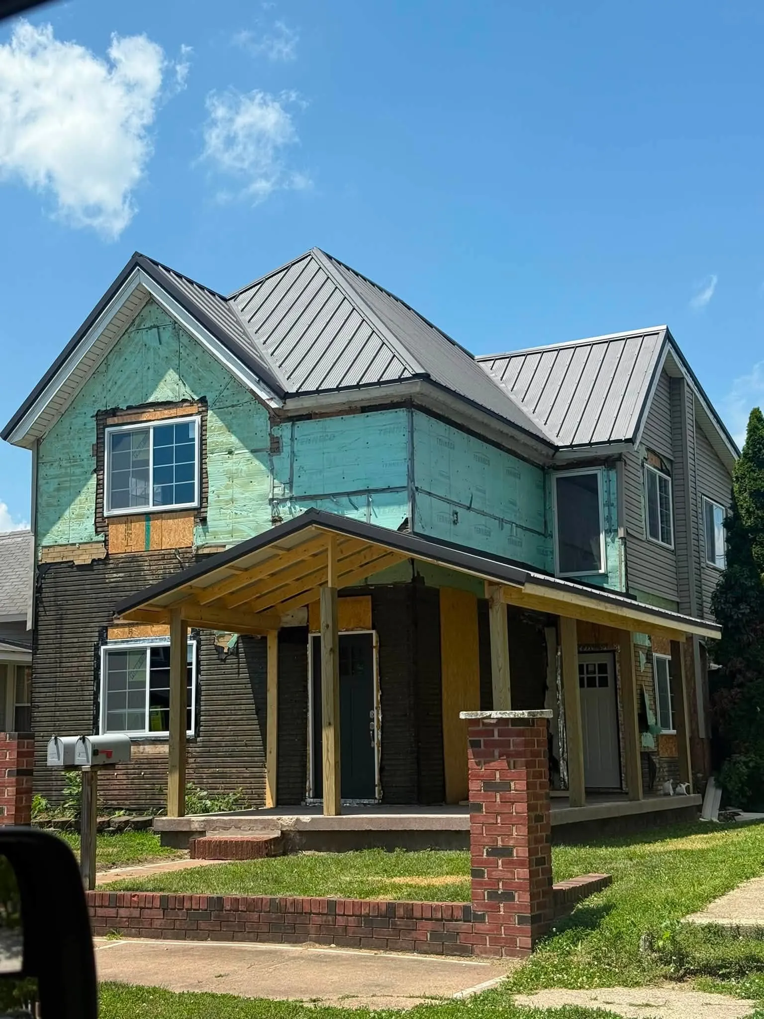 The house from the street, with the new porch framing in bare timber under its own metal roof