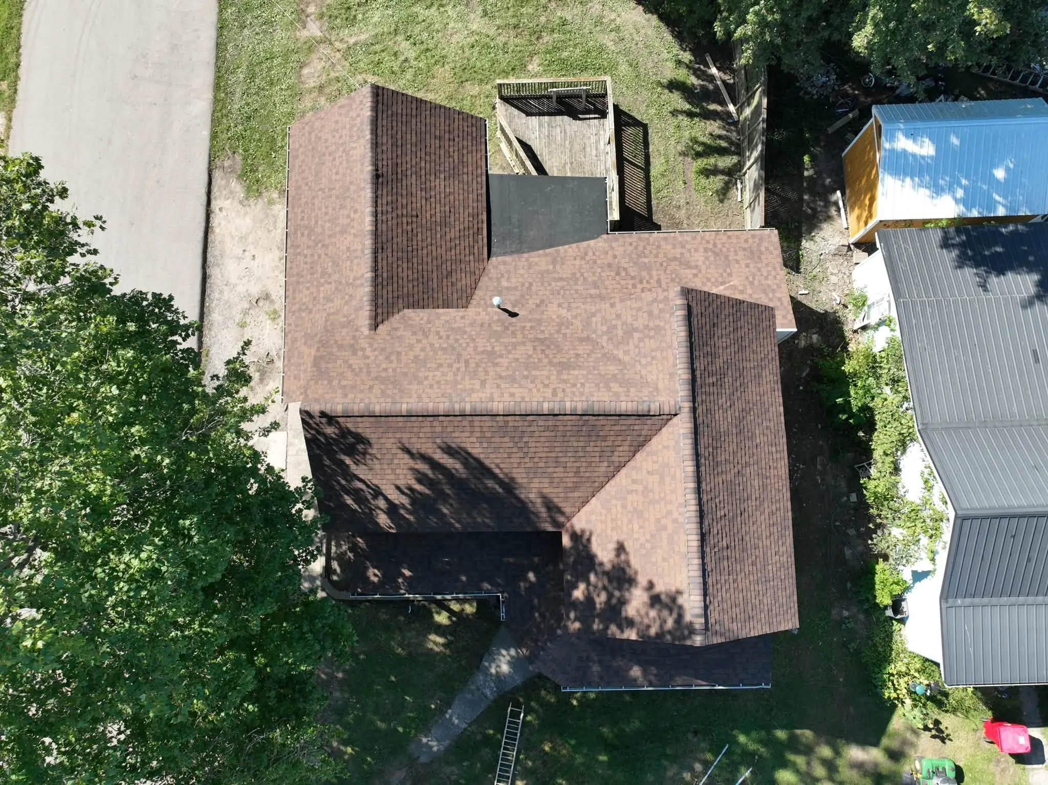 Straight-down view of the finished roof, with the neighbor's metal-roofed buildings alongside