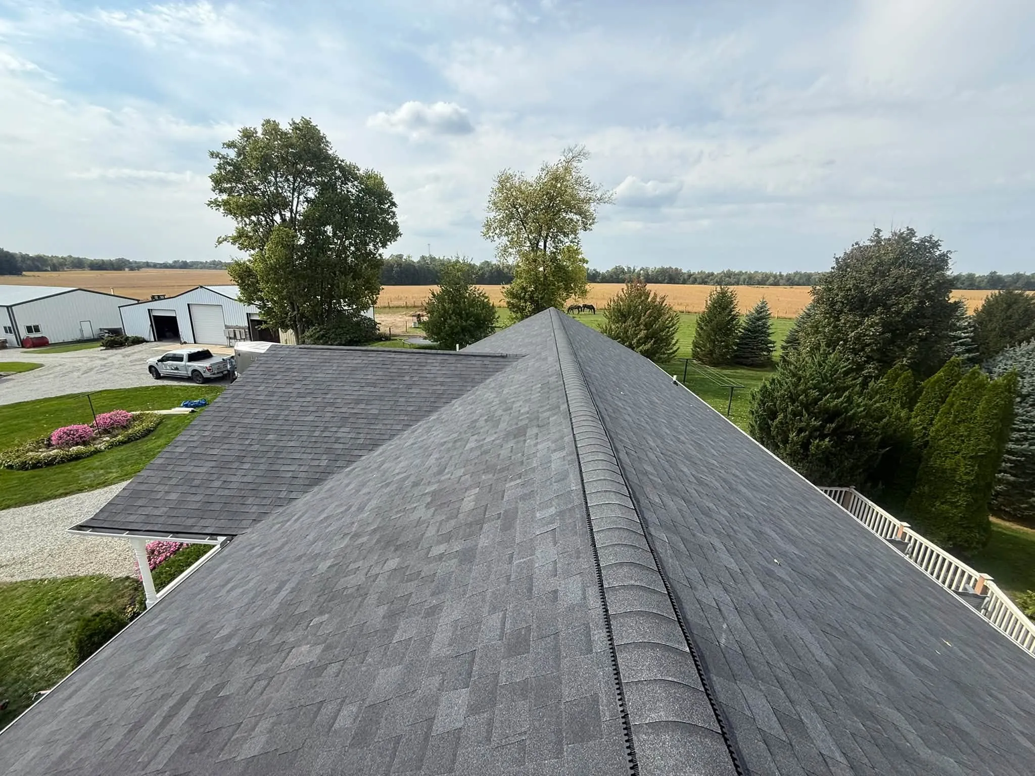 Looking along the ridge vent at the top of the new roof, toward farm buildings in the distance