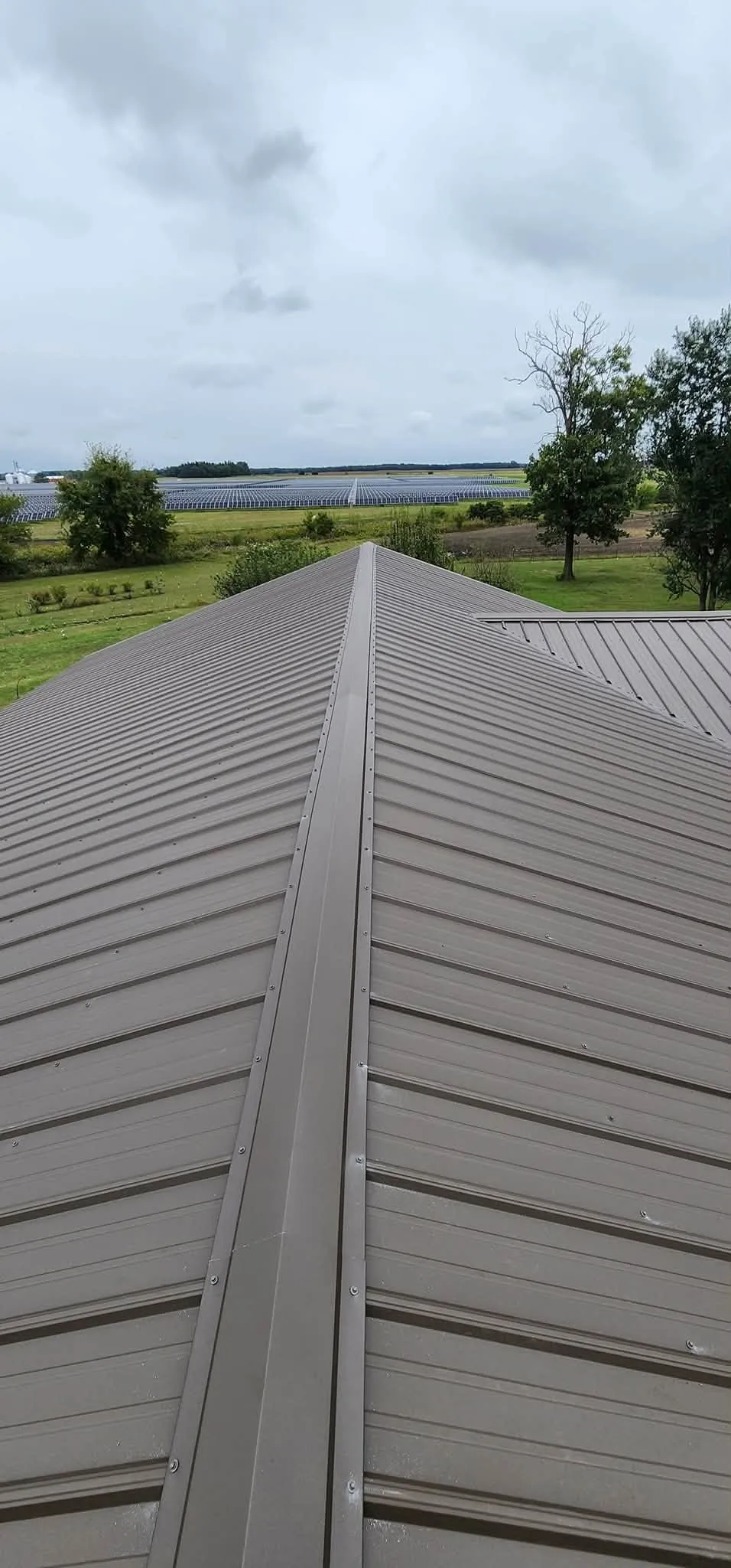 Close view up a hip, with the ridge trim running to the peak and the panels meeting it from both sides