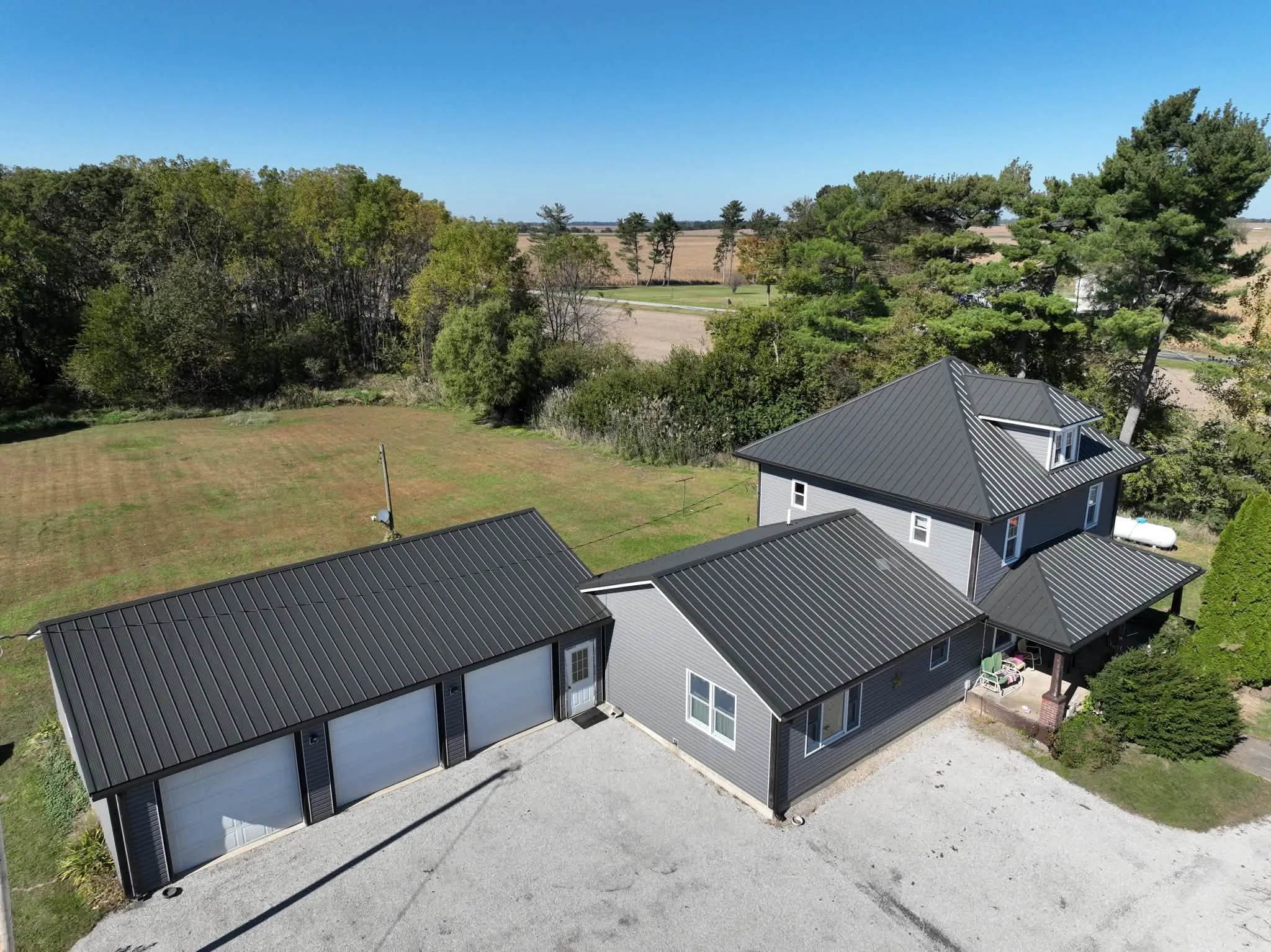 High view from the side, looking across the garage wing to the main house with fields beyond