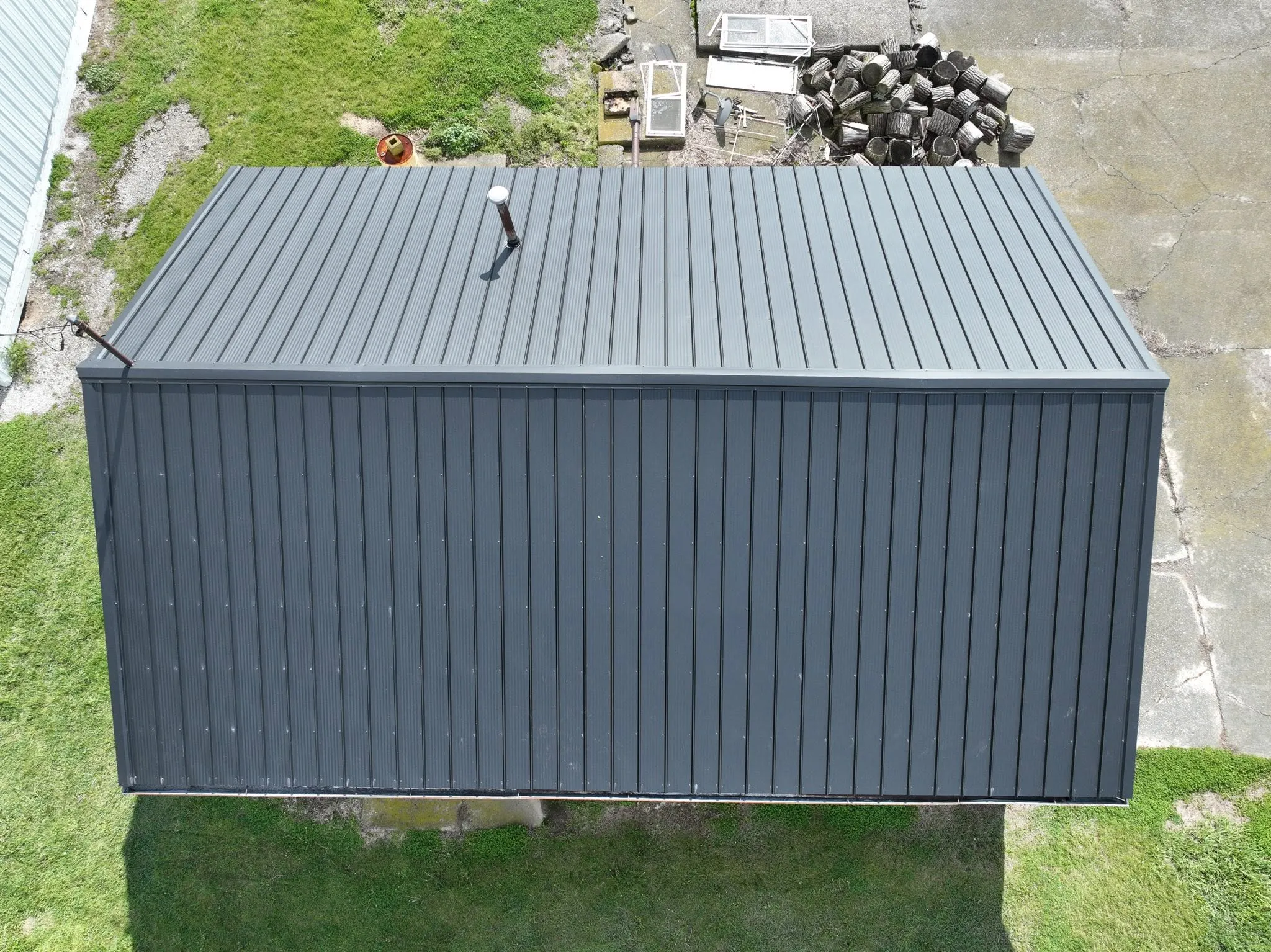 Overhead view of the completed black metal roof with ridge cap and vent boot