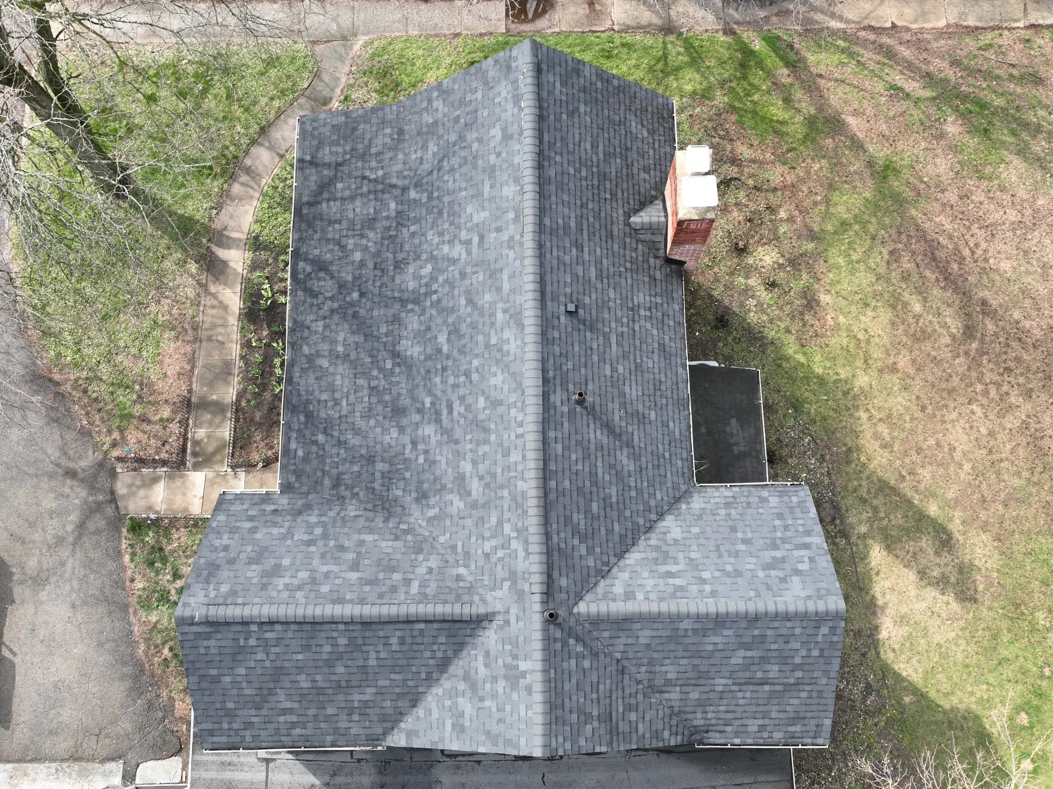 Overhead view of the finished gray shingle roof and the brick chimney