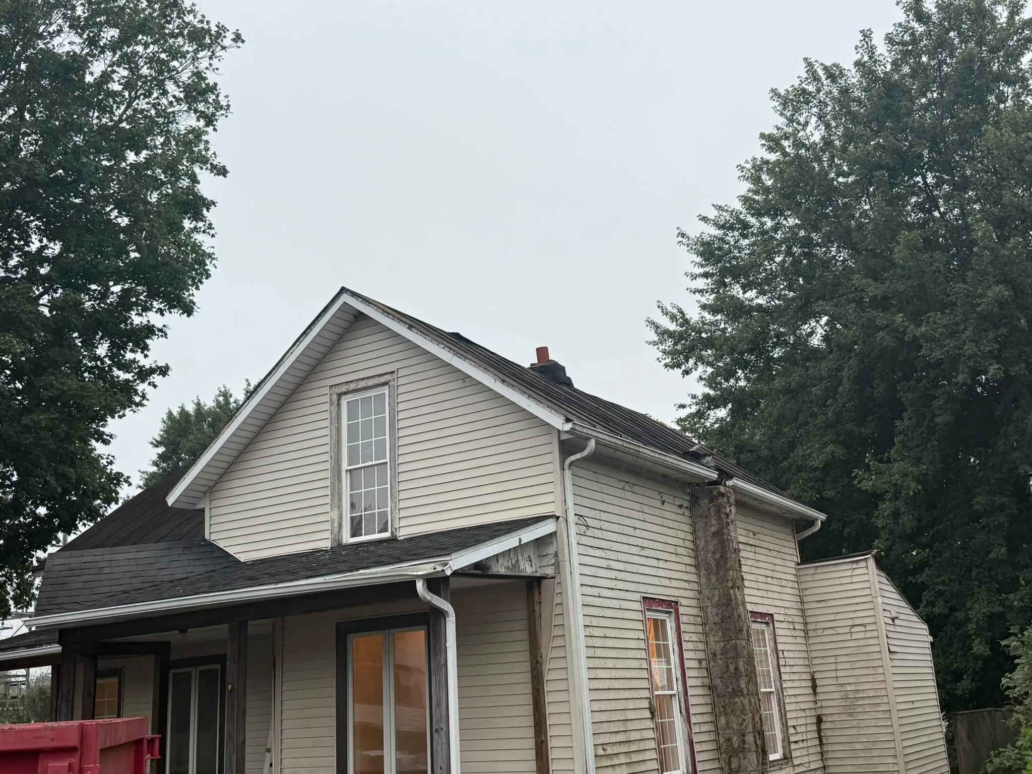The house from the ground before the work, with the dumpster pulled up beside the porch