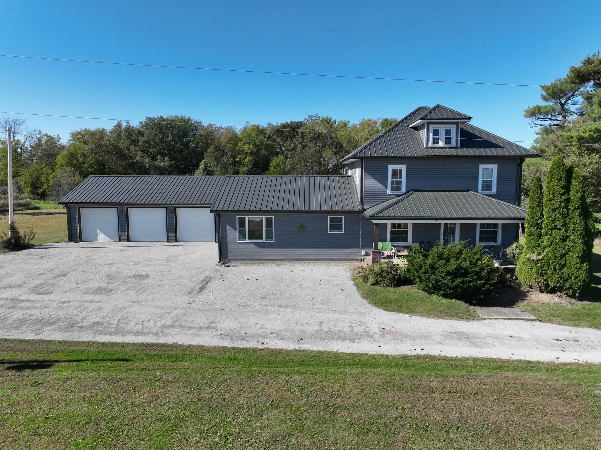 The whole place from across the gravel drive, with the three-bay garage on the left and the house on the right