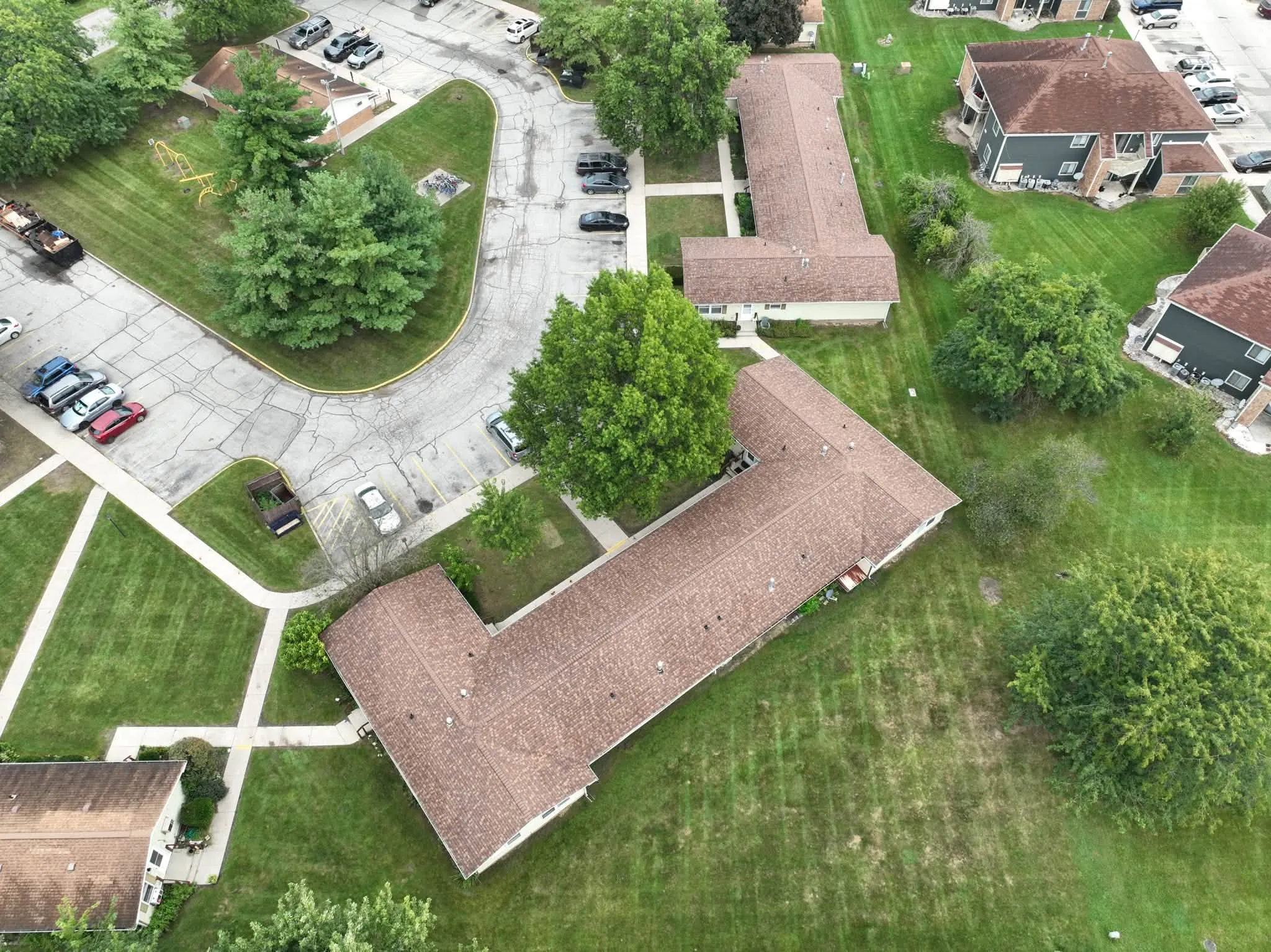 High view across the complex, with one of the reroofed buildings in the foreground and the parking lot curving around it