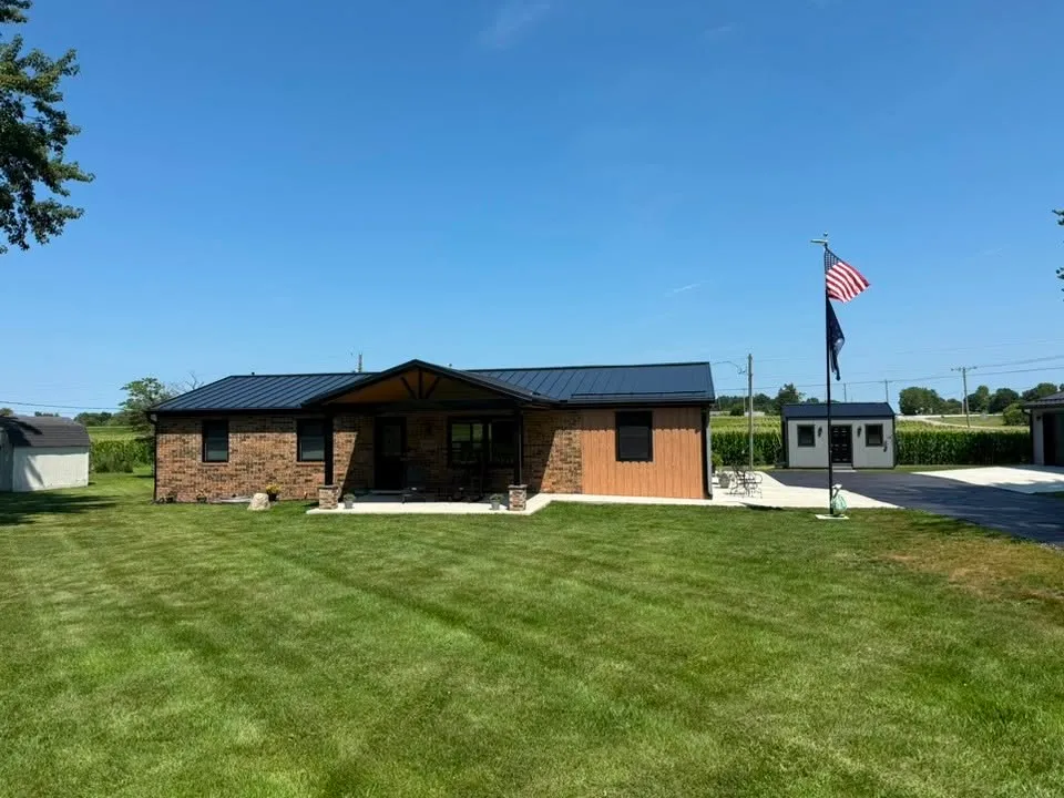 The front of the finished house at eye level across the lawn, with the flag flying beside the driveway