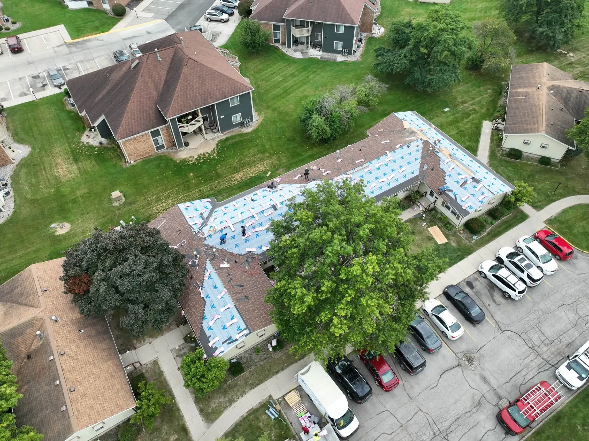 Overhead view mid-job, with one building in underlayment and the parking lot full of cars