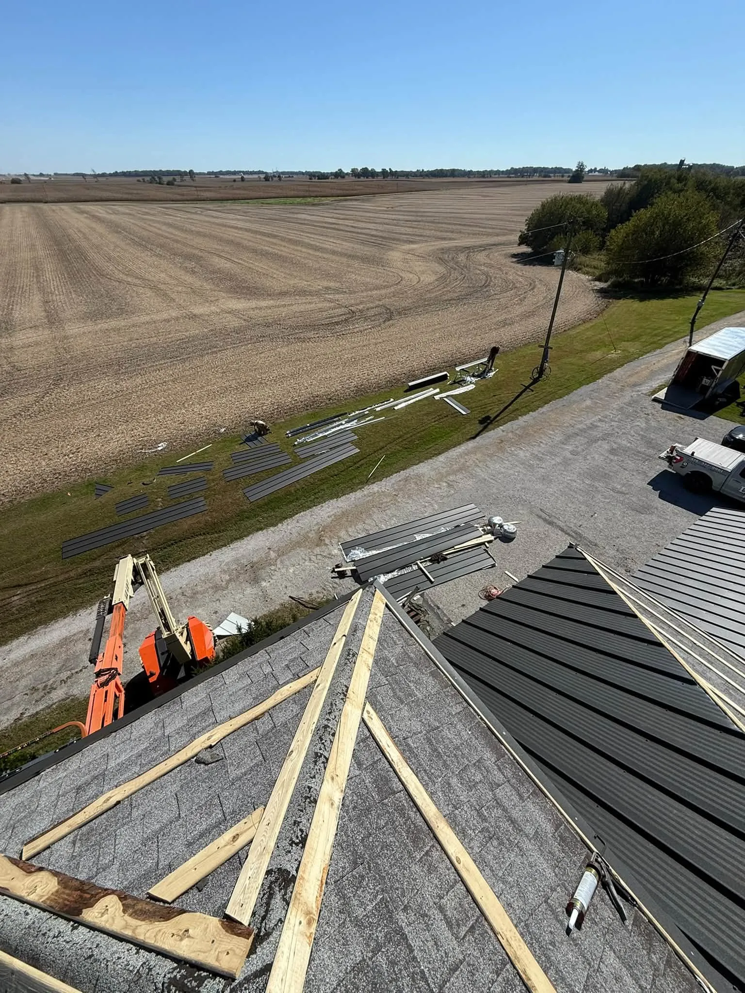 Looking down from the roof as the new panels go on, with more panels and trim staged in the yard below