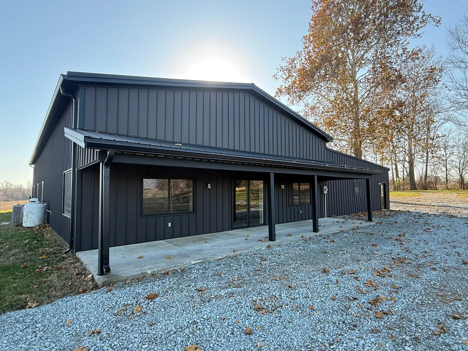 A dark metal garage with a covered porch and black support posts