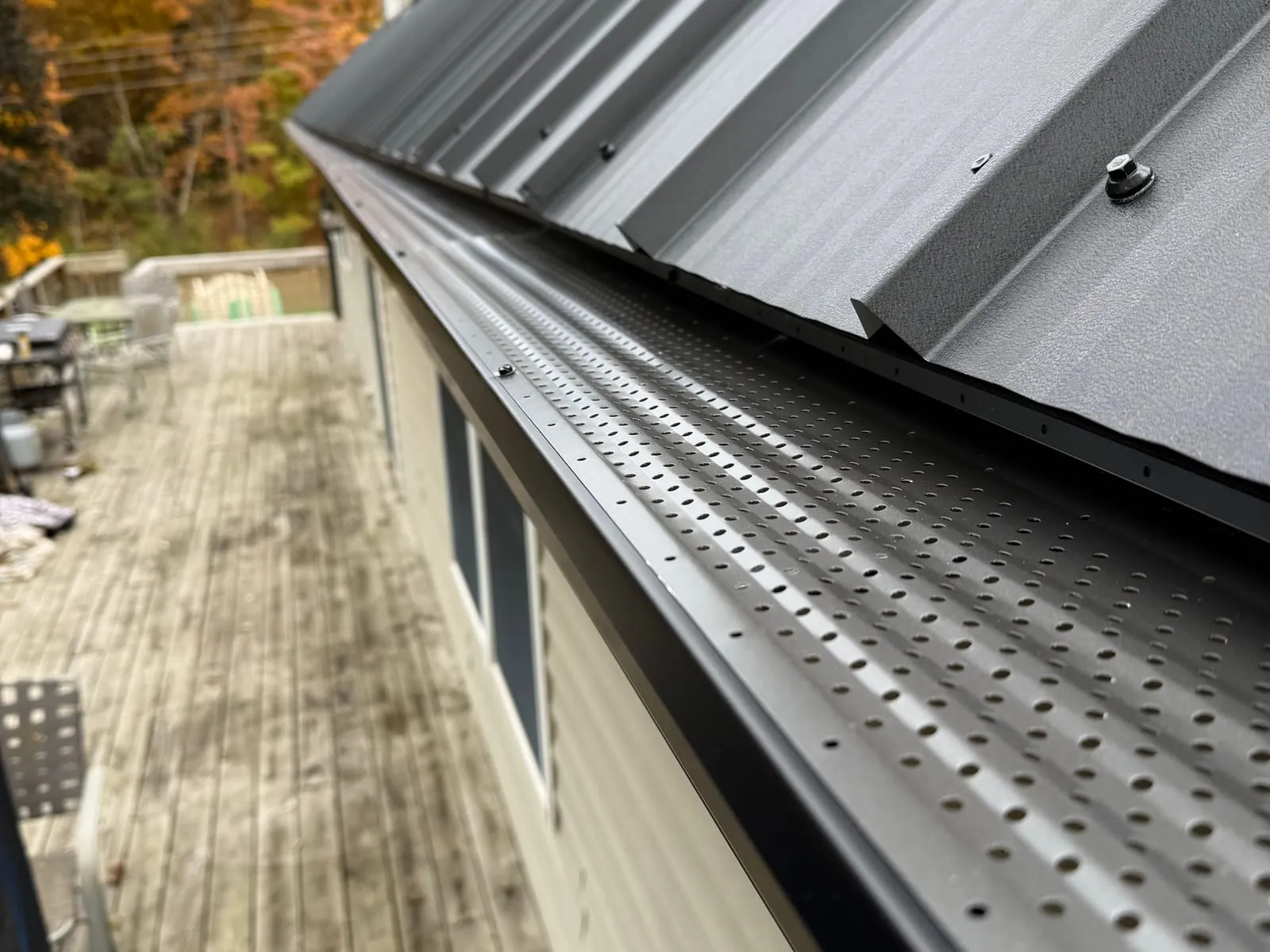 Close-up of a dark seamless gutter run along a metal roof edge