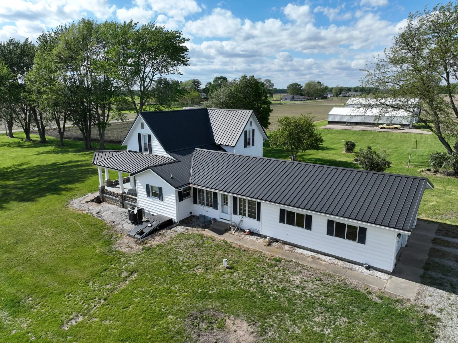 White farmhouse with a silver standing-seam metal roof